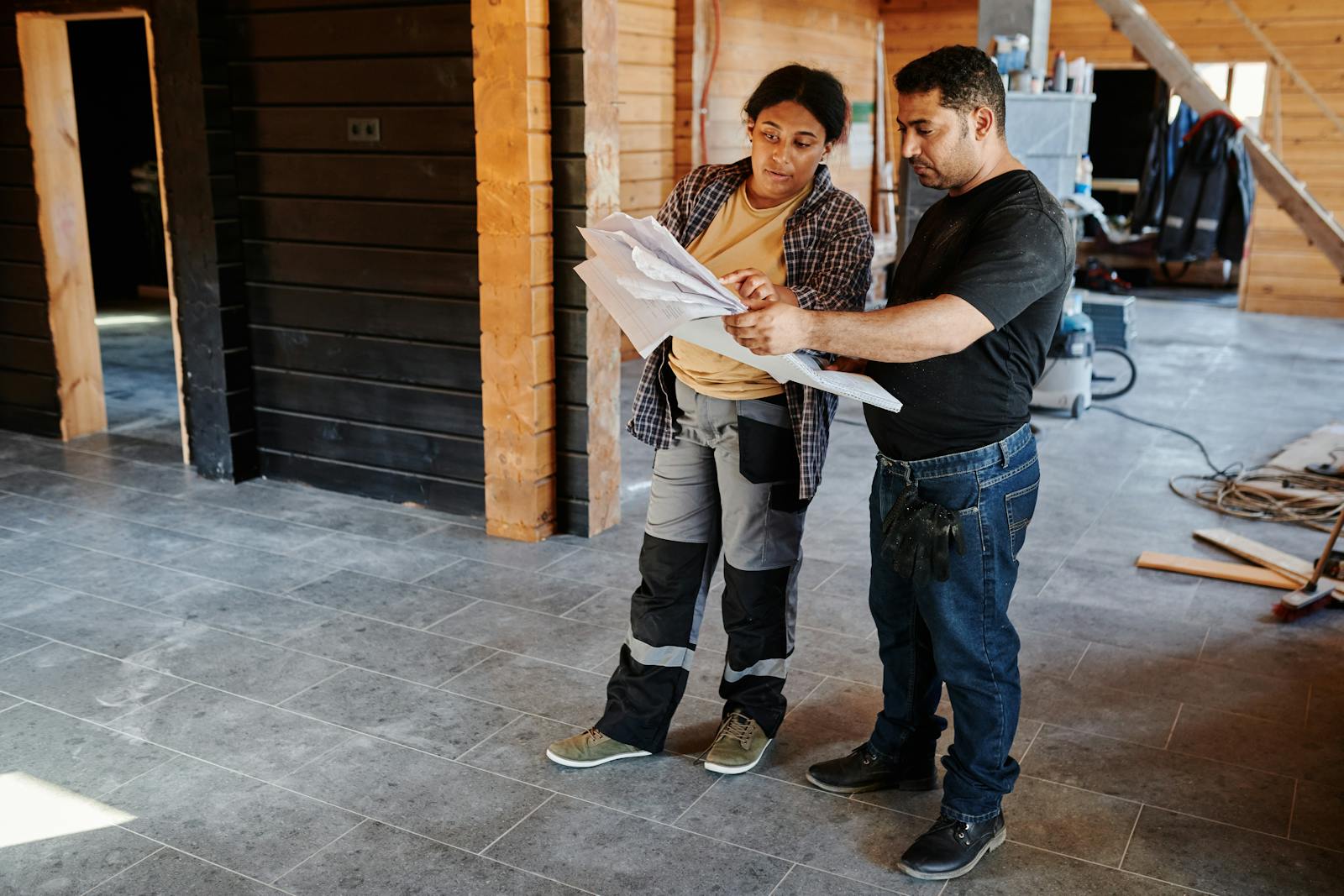Two contractors reviewing renovation blueprints inside a home under construction