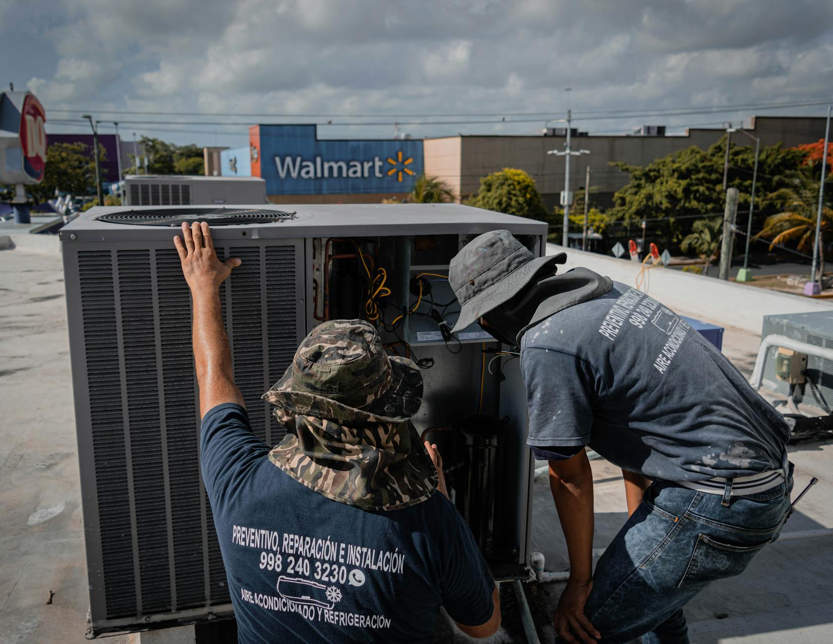 Two HVAC technicians performing rooftop unit maintenance