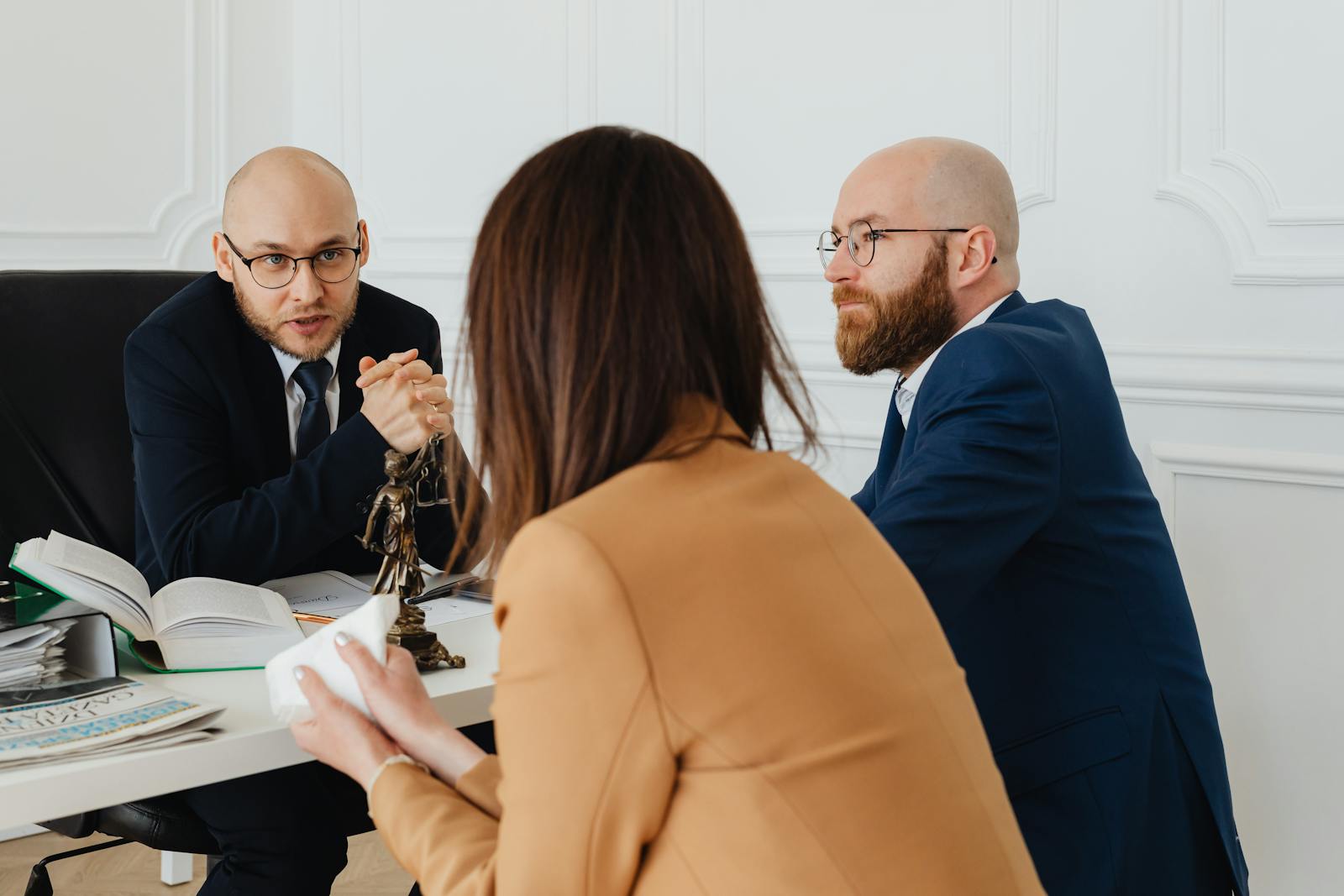 Two attorneys discussing case strategy with a female client across a desk