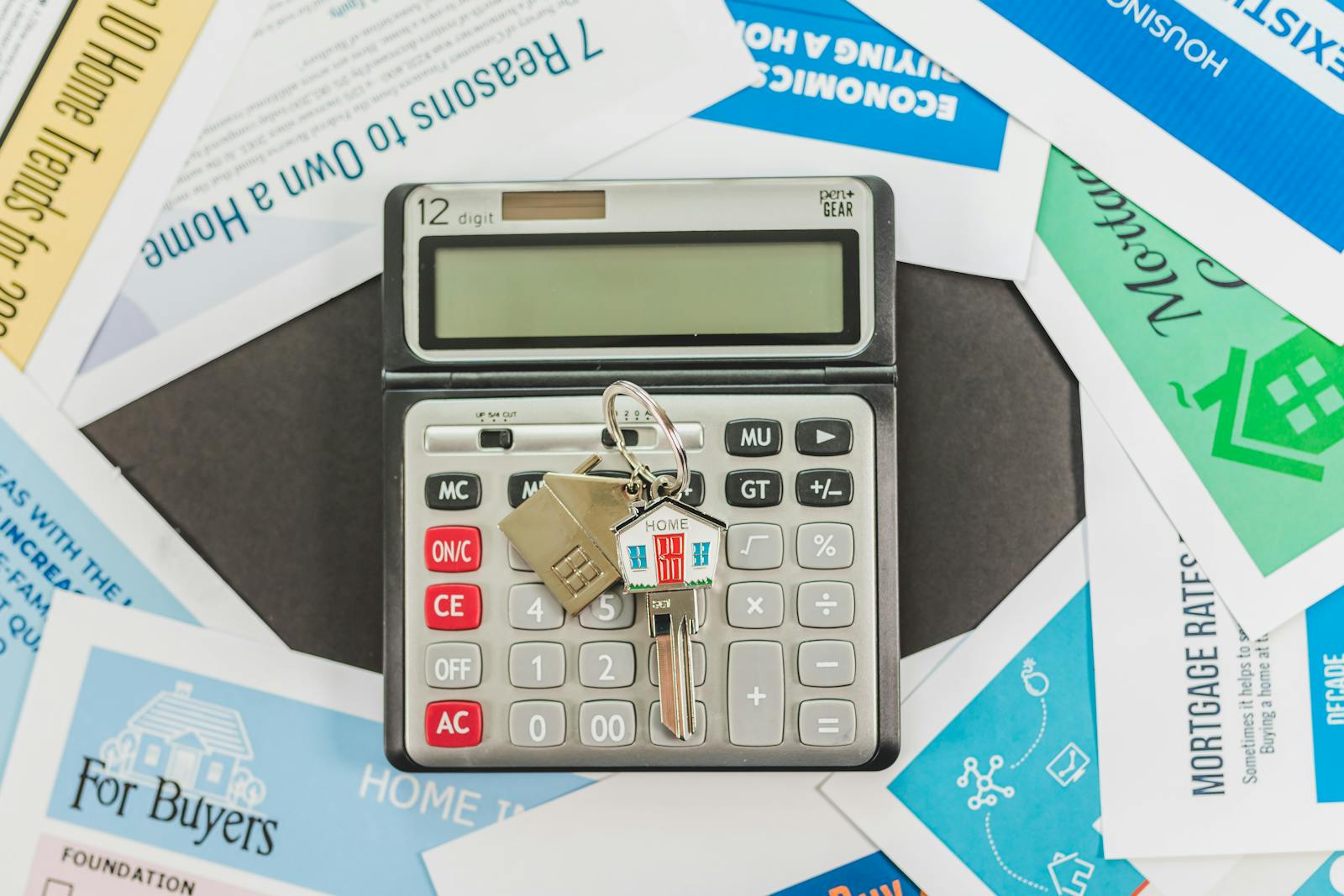 Calculator and house keys placed on closing cost documents on a desk