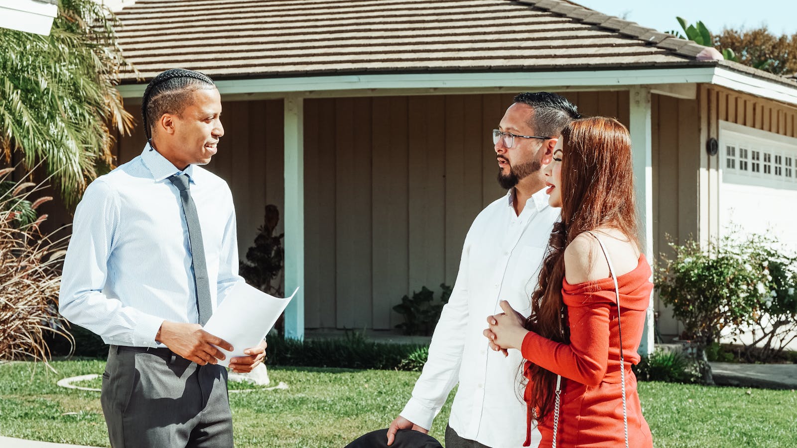 A real estate professional discussing property details with a couple in front of a home