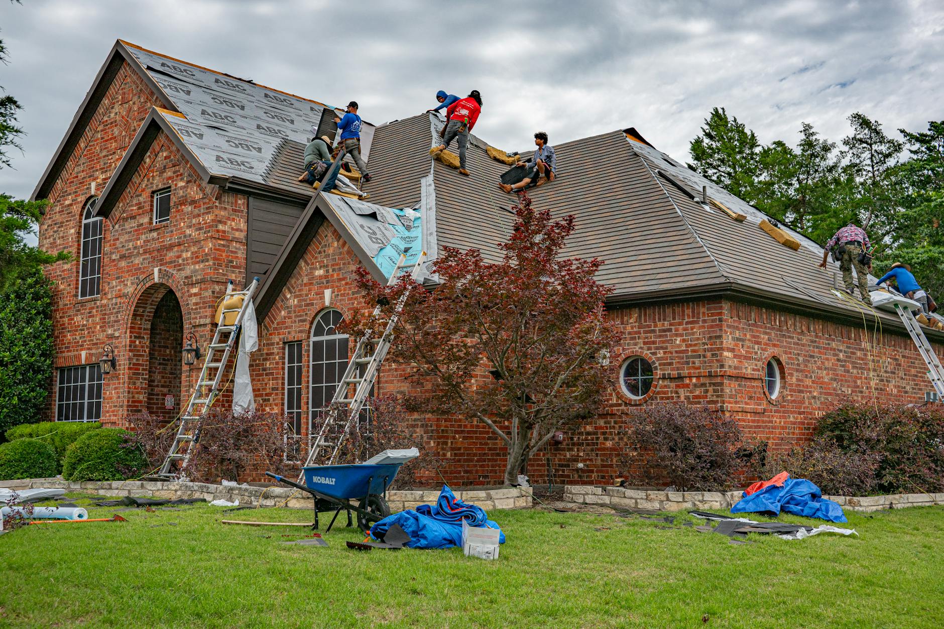 Roofing crew replacing shingles on a brick residential home