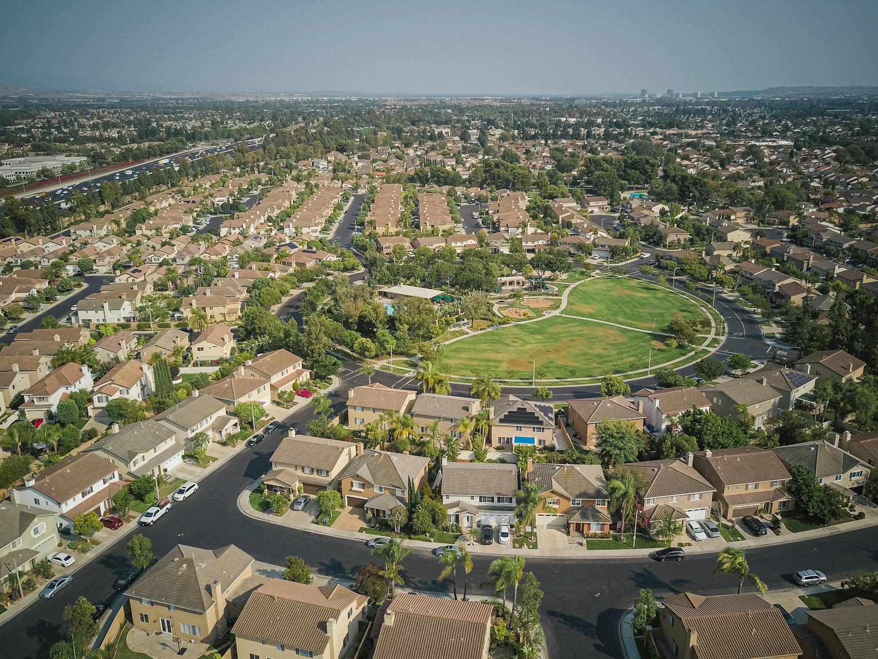 Aerial view of a suburban neighborhood with a park and detached homes