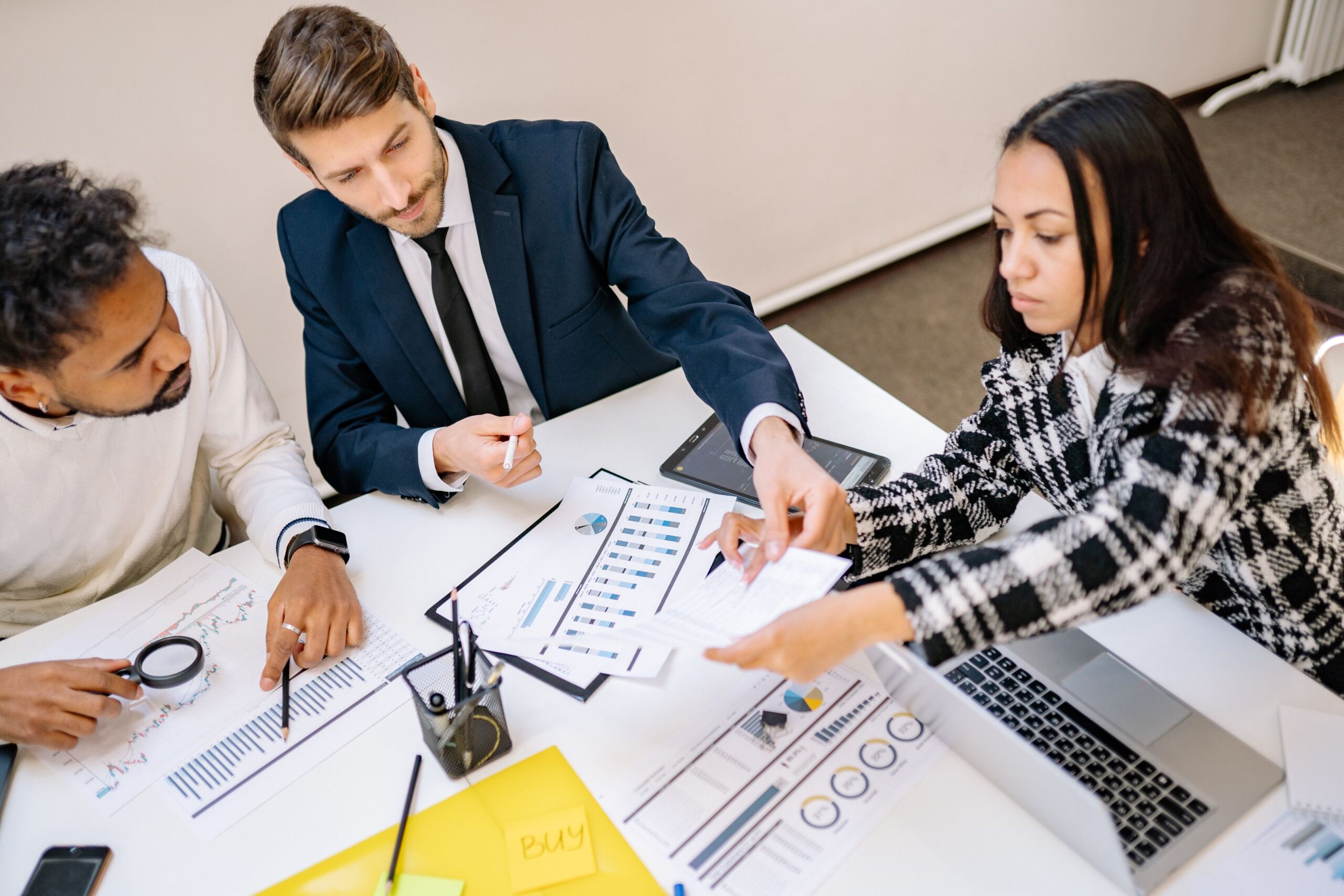 A small team reviewing analytics charts and reports around a table during a strategy meeting
