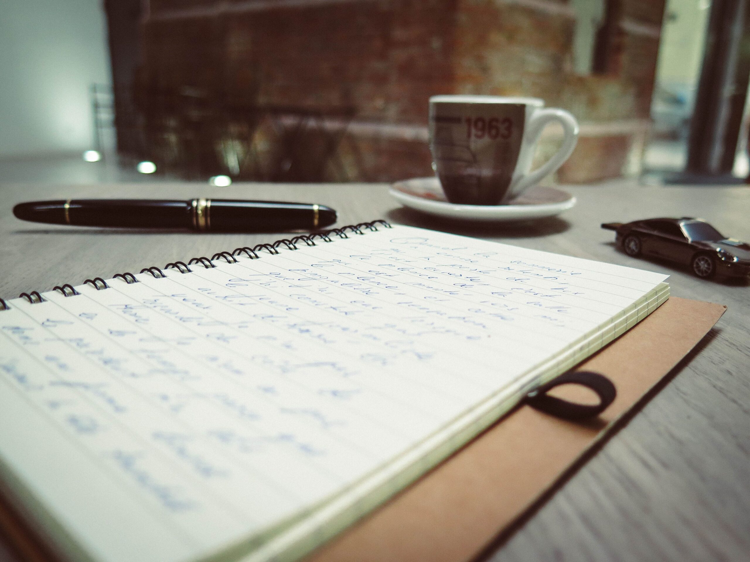 A handwritten notebook beside an espresso cup, representing editing and adding human detail to a draft