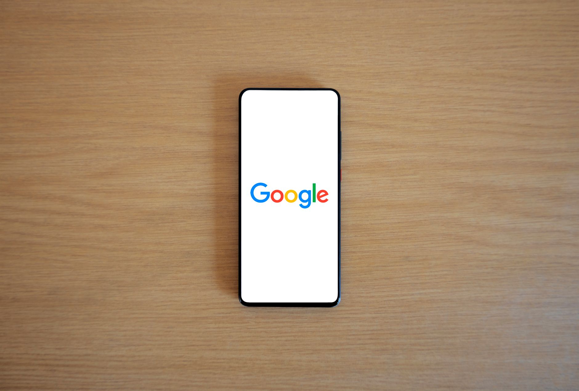 Smartphone displaying the Google search page on a wooden surface, illustrating how patients begin a chiropractor near me search