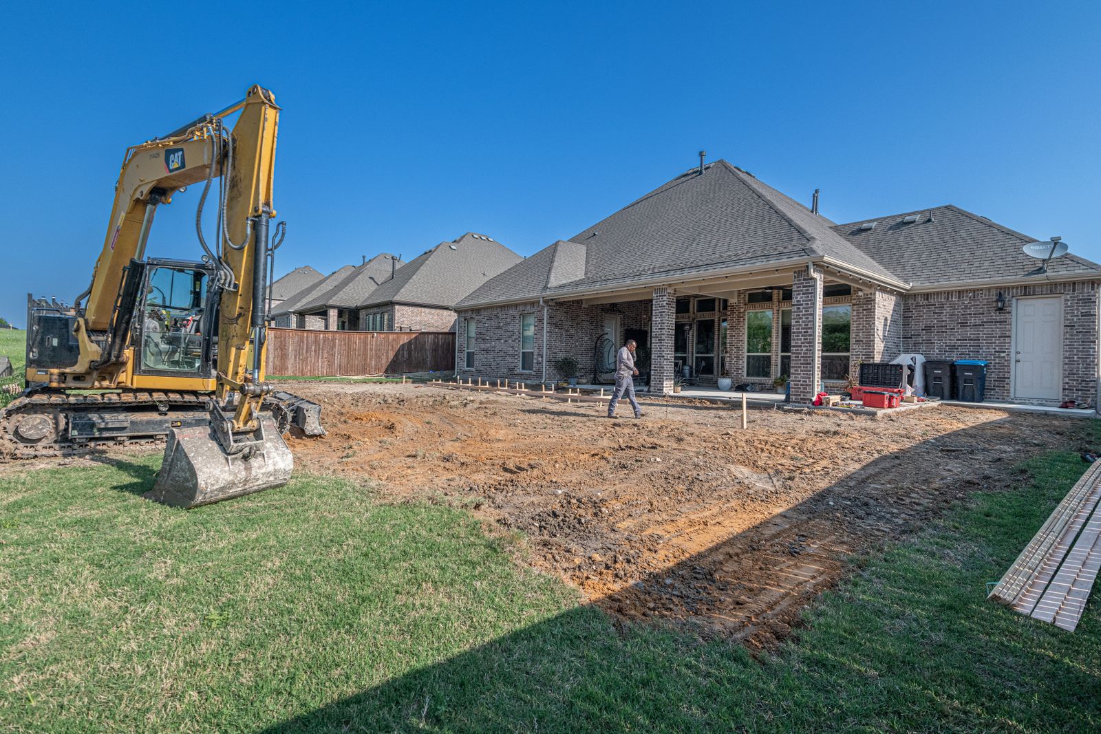 Excavator preparing a residential backyard for a new concrete patio project