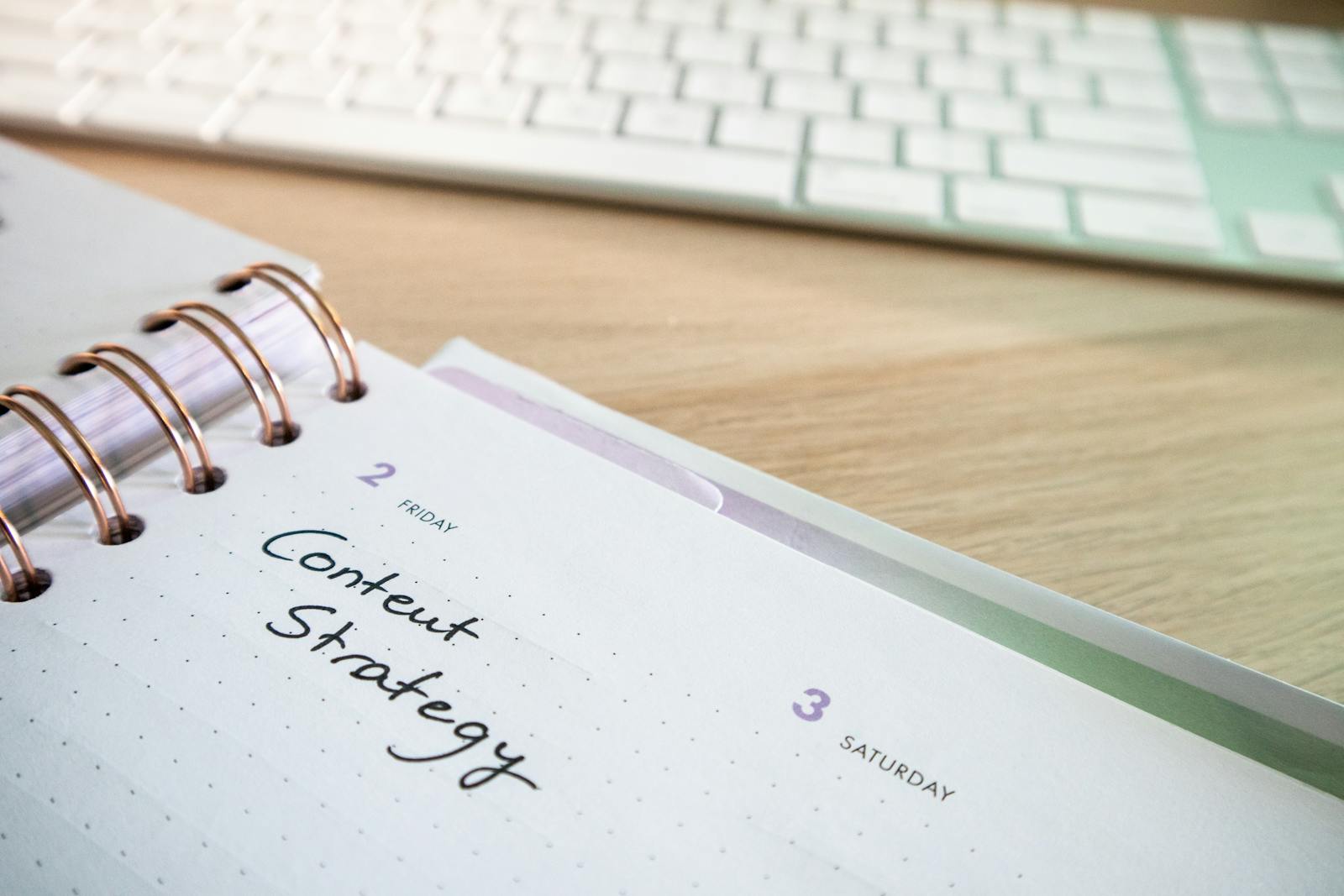 Open planner showing handwritten content strategy schedule next to a keyboard