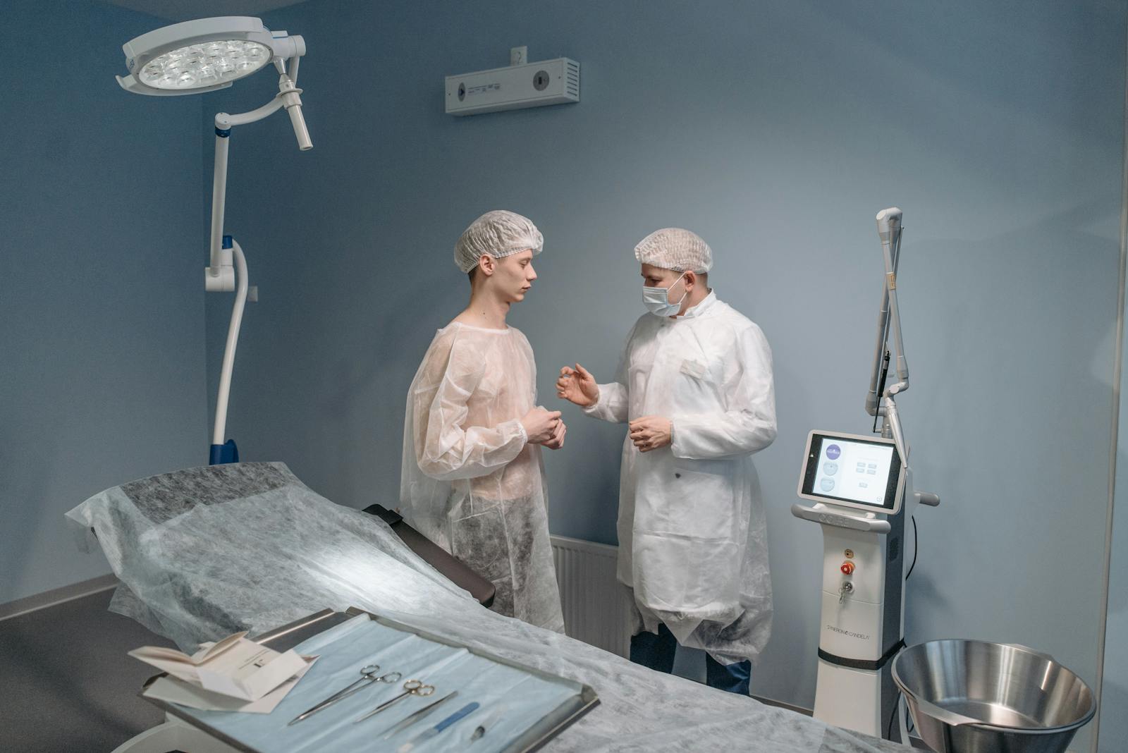 Cosmetic surgeons in protective gowns reviewing procedure details in a sterile clinical room