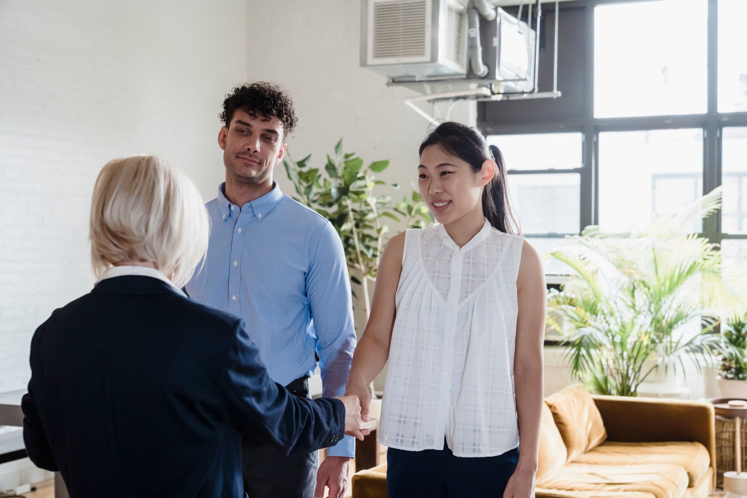 Young couple shaking hands with a real estate agent after closing a deal