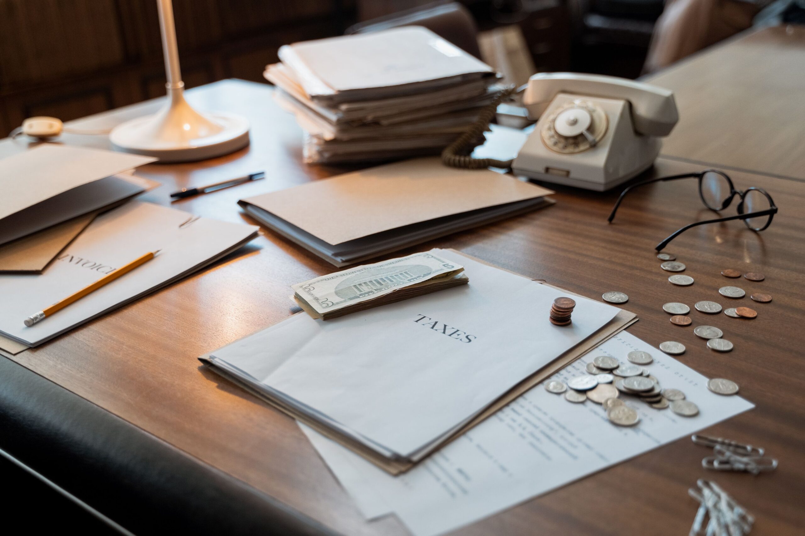 Tax documents, cash, and coins spread across an accountant's desk during the busy season