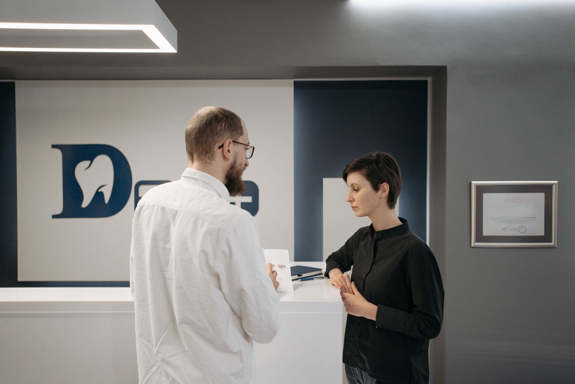 Patient checking in at a dental clinic front desk with a staff member