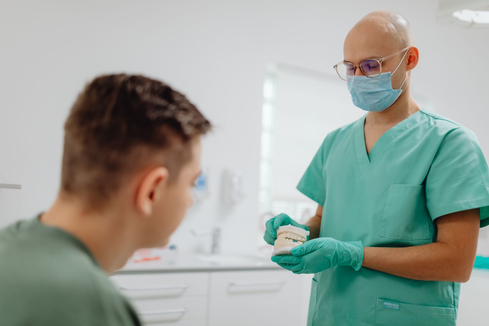 Dentist holding a dental model and explaining treatment to a patient