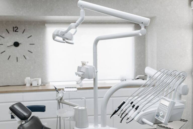 Modern dental treatment room with a patient chair, overhead light, and instruments