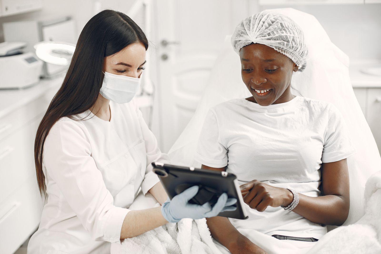 Dermatologist showing skincare information to a smiling patient on a tablet during a consultation