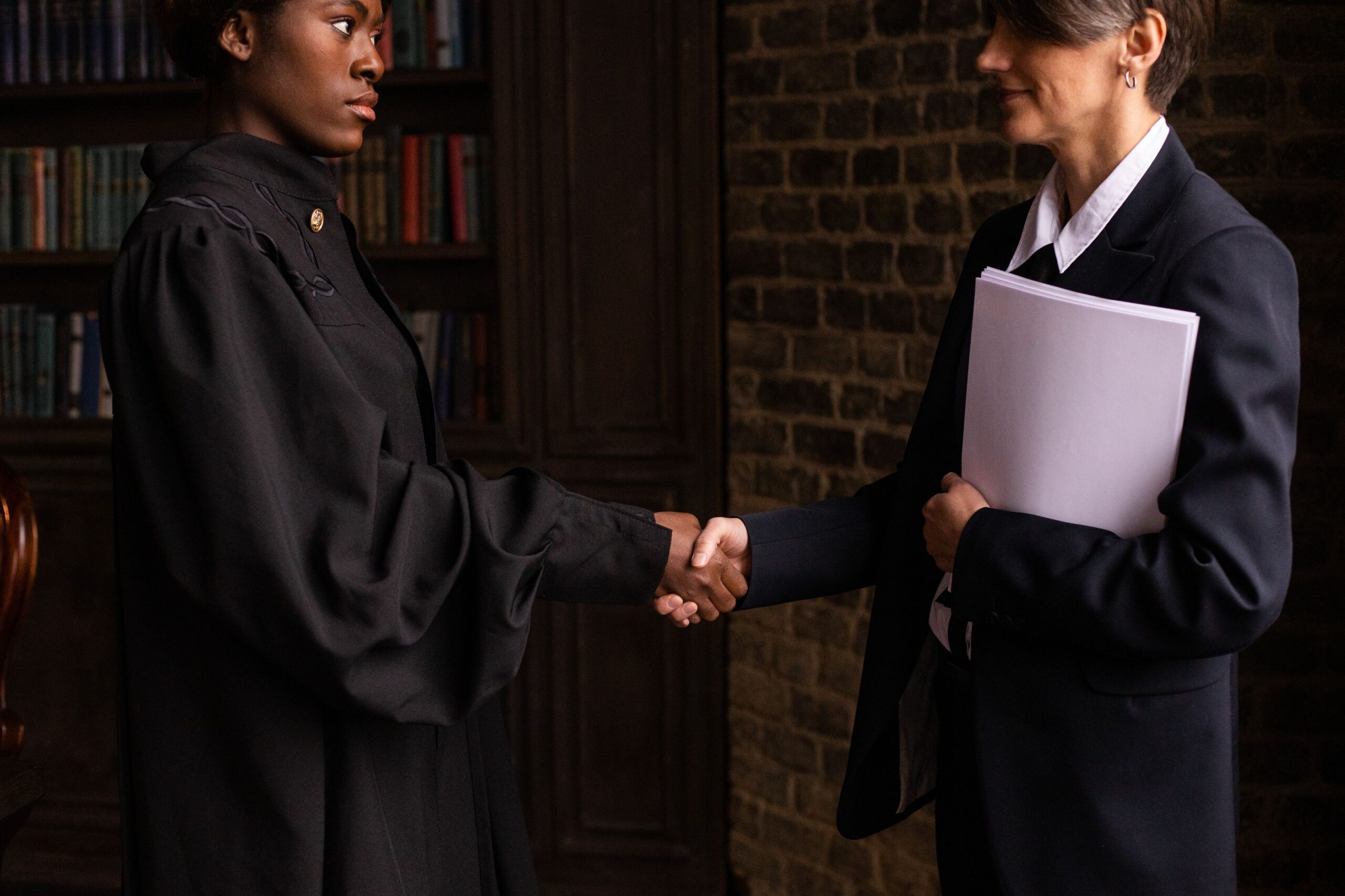 An attorney shaking hands with a client in a law library after a successful case