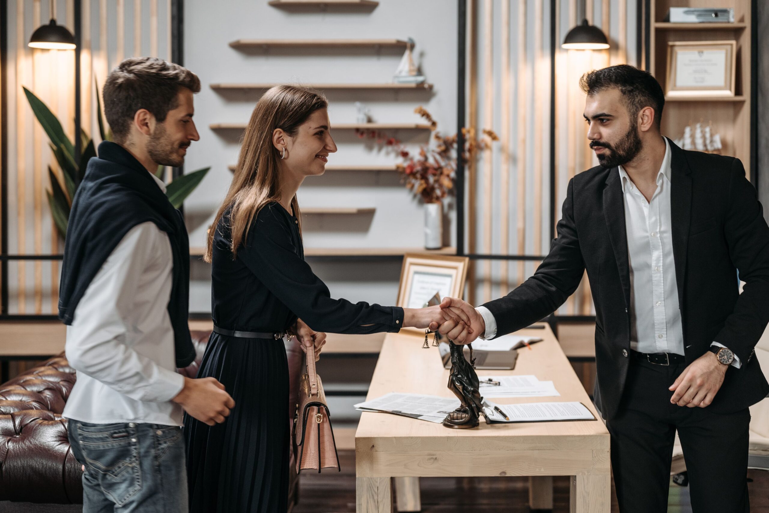 A husband and wife shaking hands with their family lawyer at the start of a case