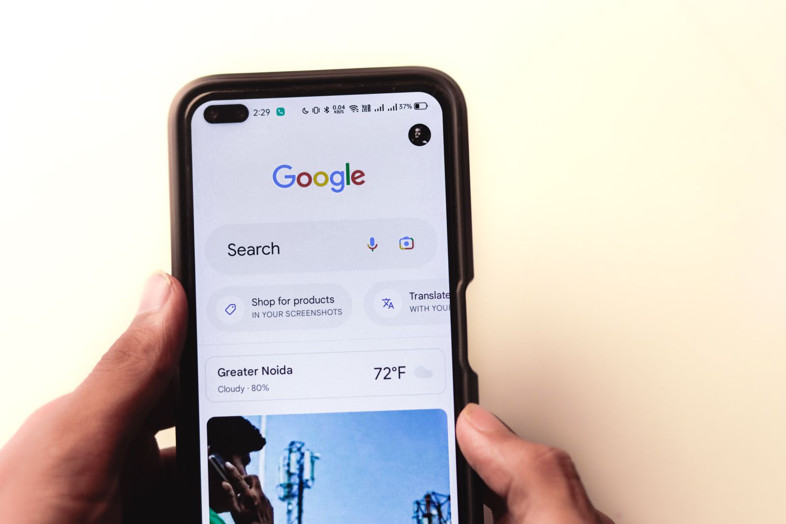 Hand holding a smartphone displaying the Google search homepage