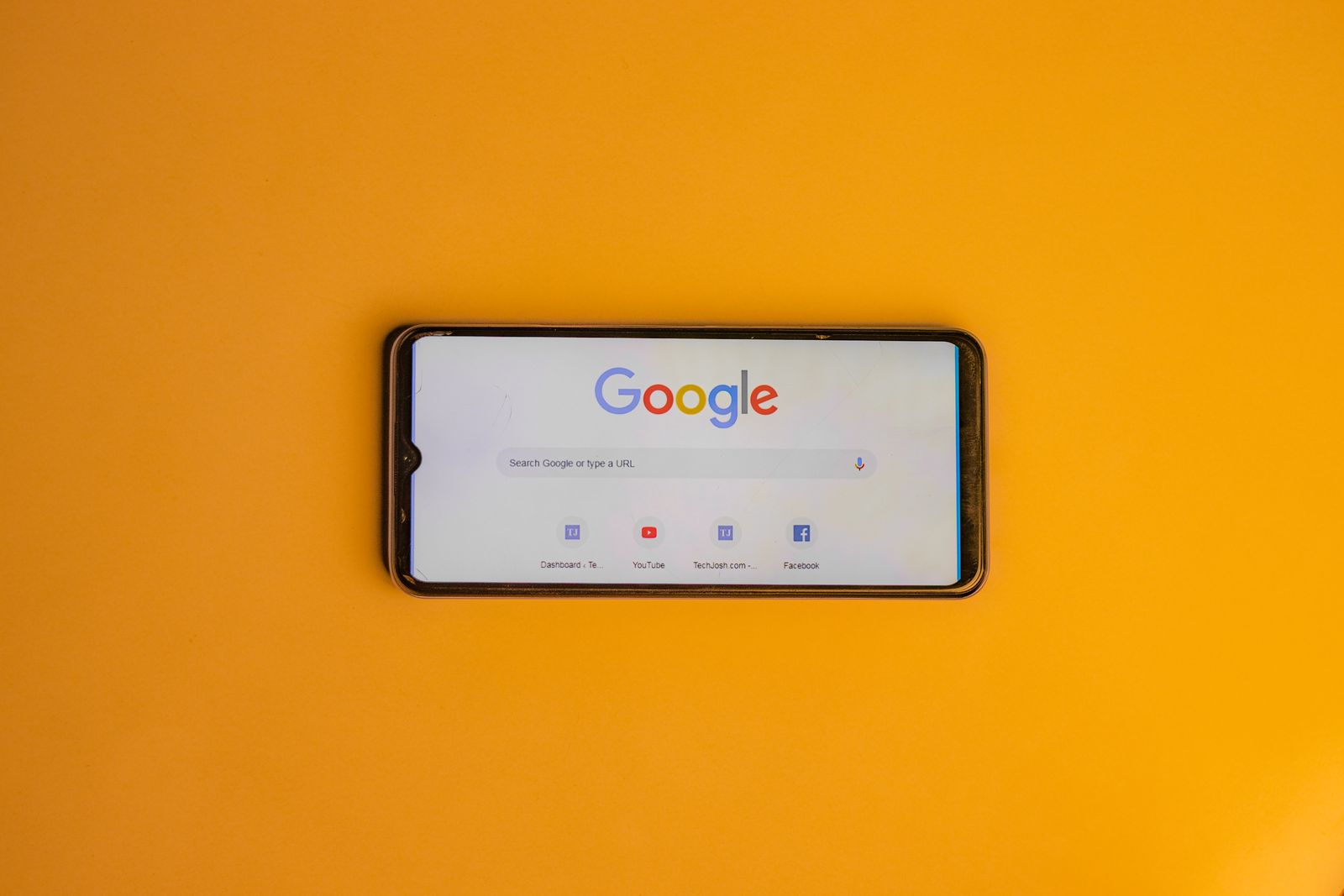 Smartphone showing the Google search page on a yellow background