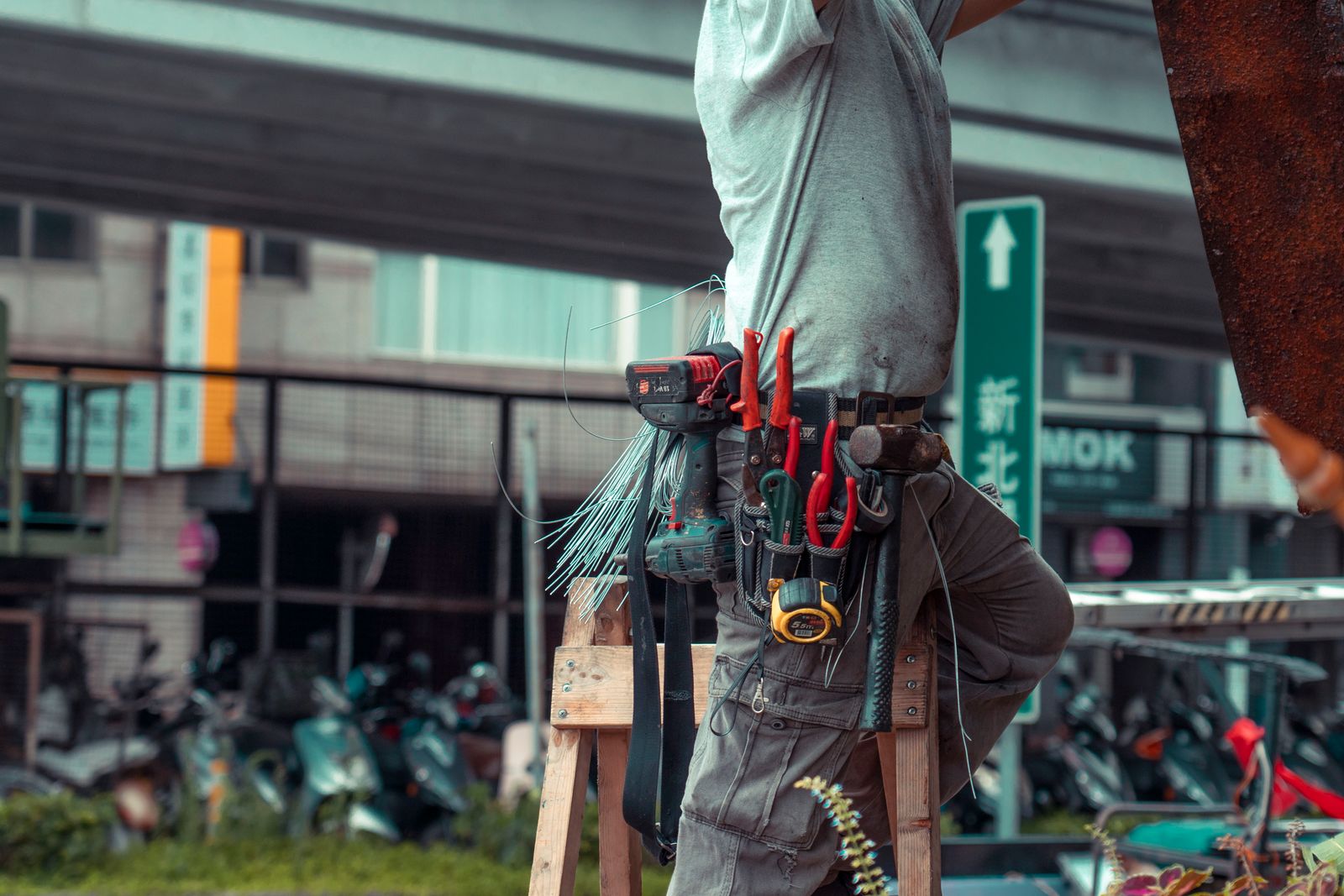 Service technician with a loaded tool belt on a ladder during a job