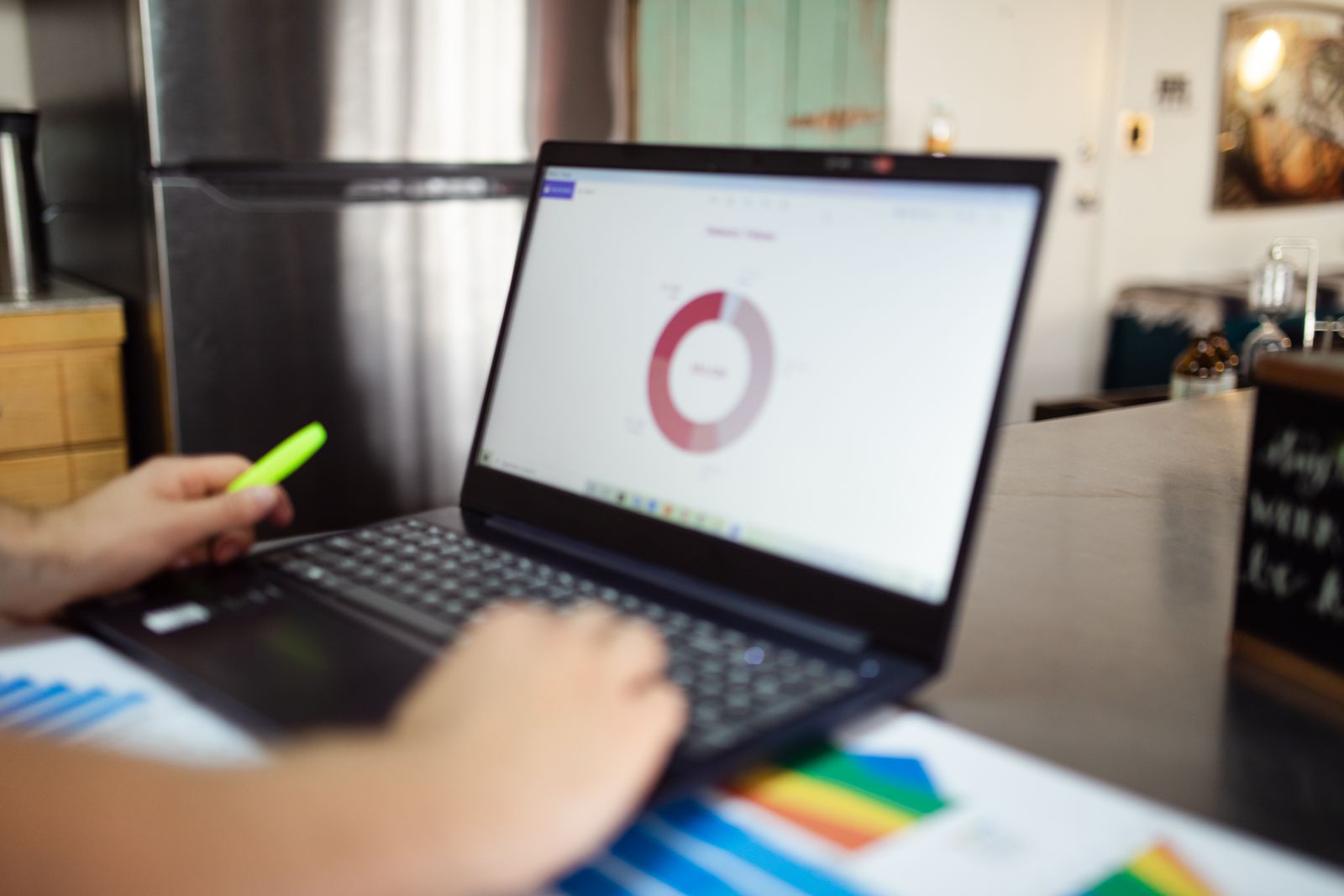 Small business owner reviewing analytics on laptop with printed charts beside it