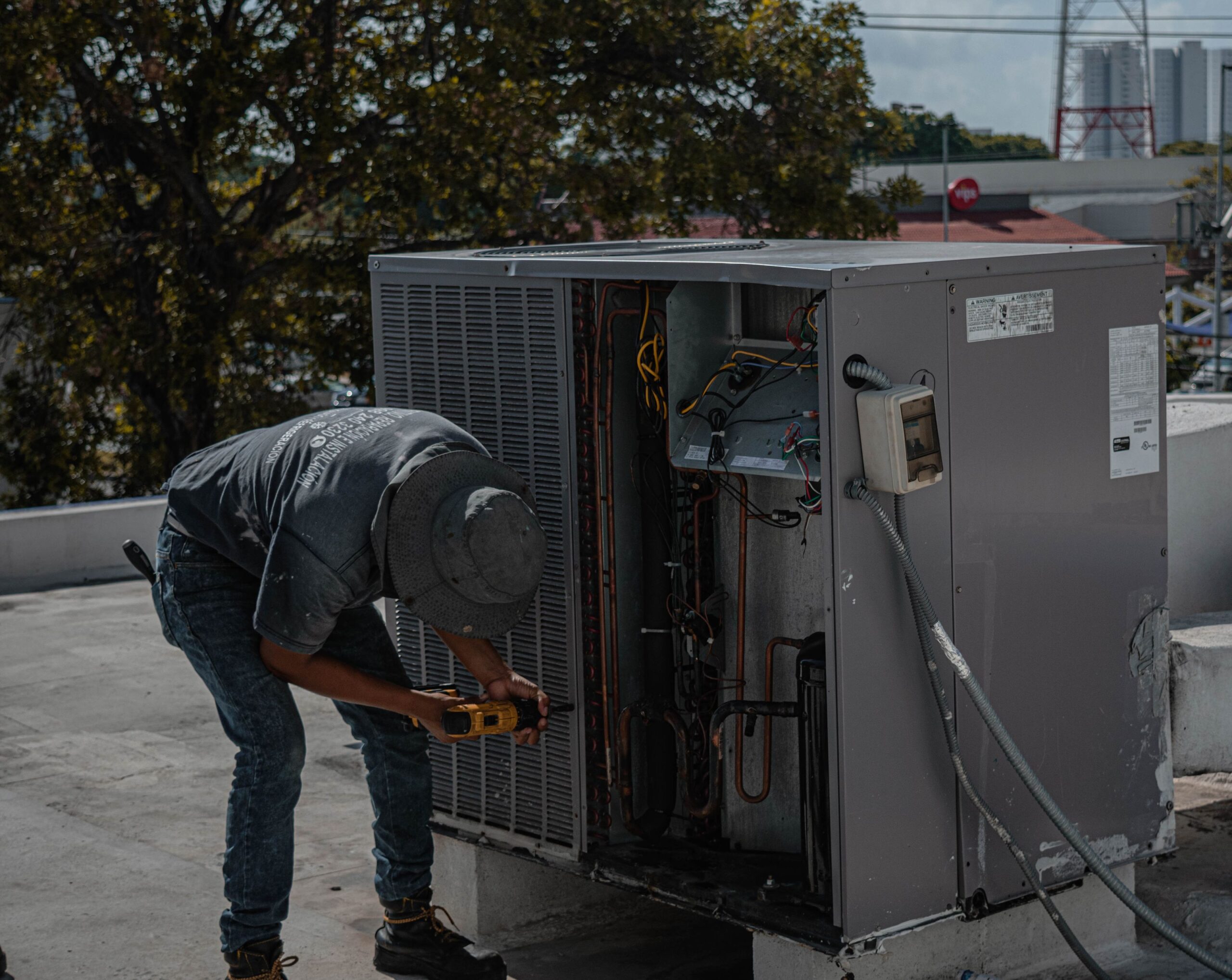 HVAC technician servicing the internal wiring of a rooftop air conditioning condenser unit