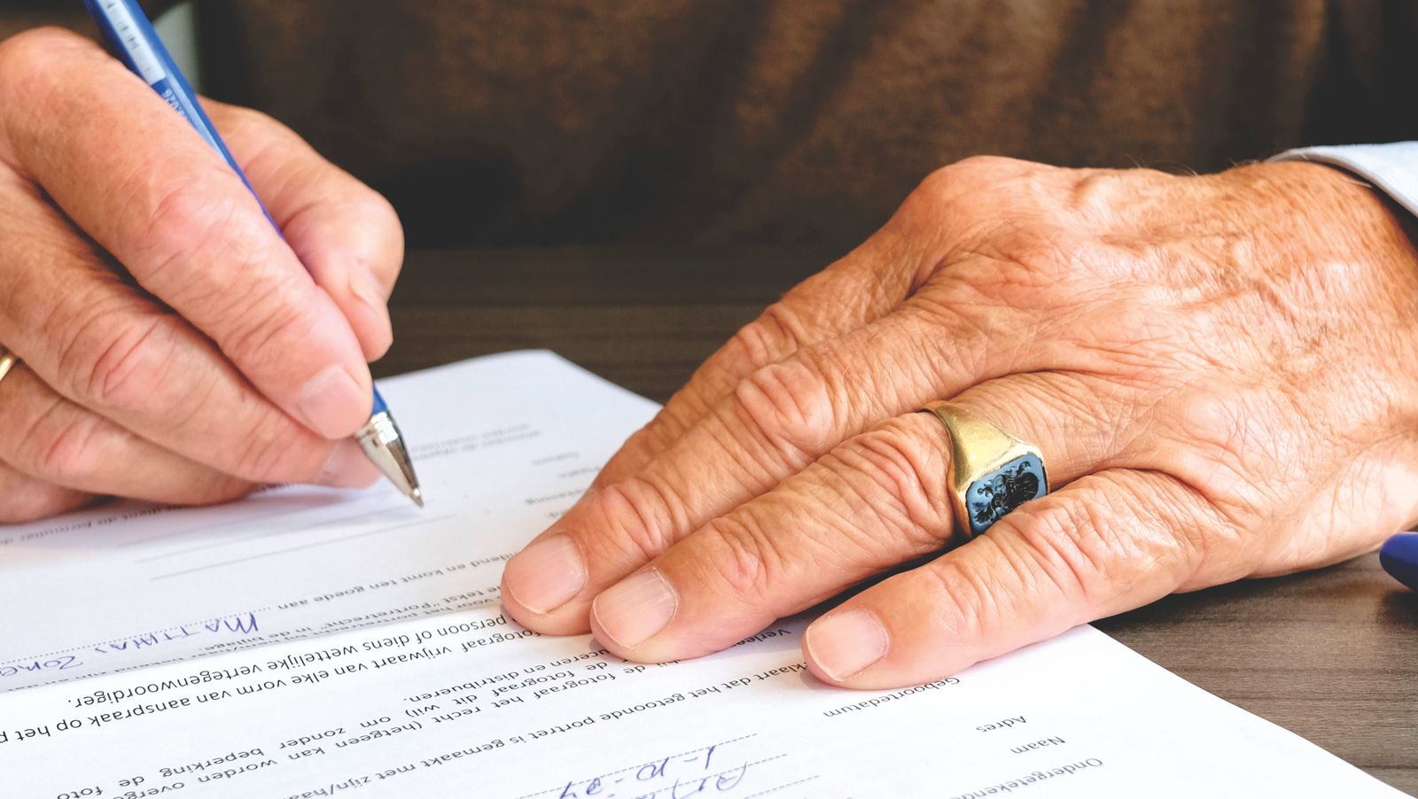 Senior client signing an estate planning document with a pen