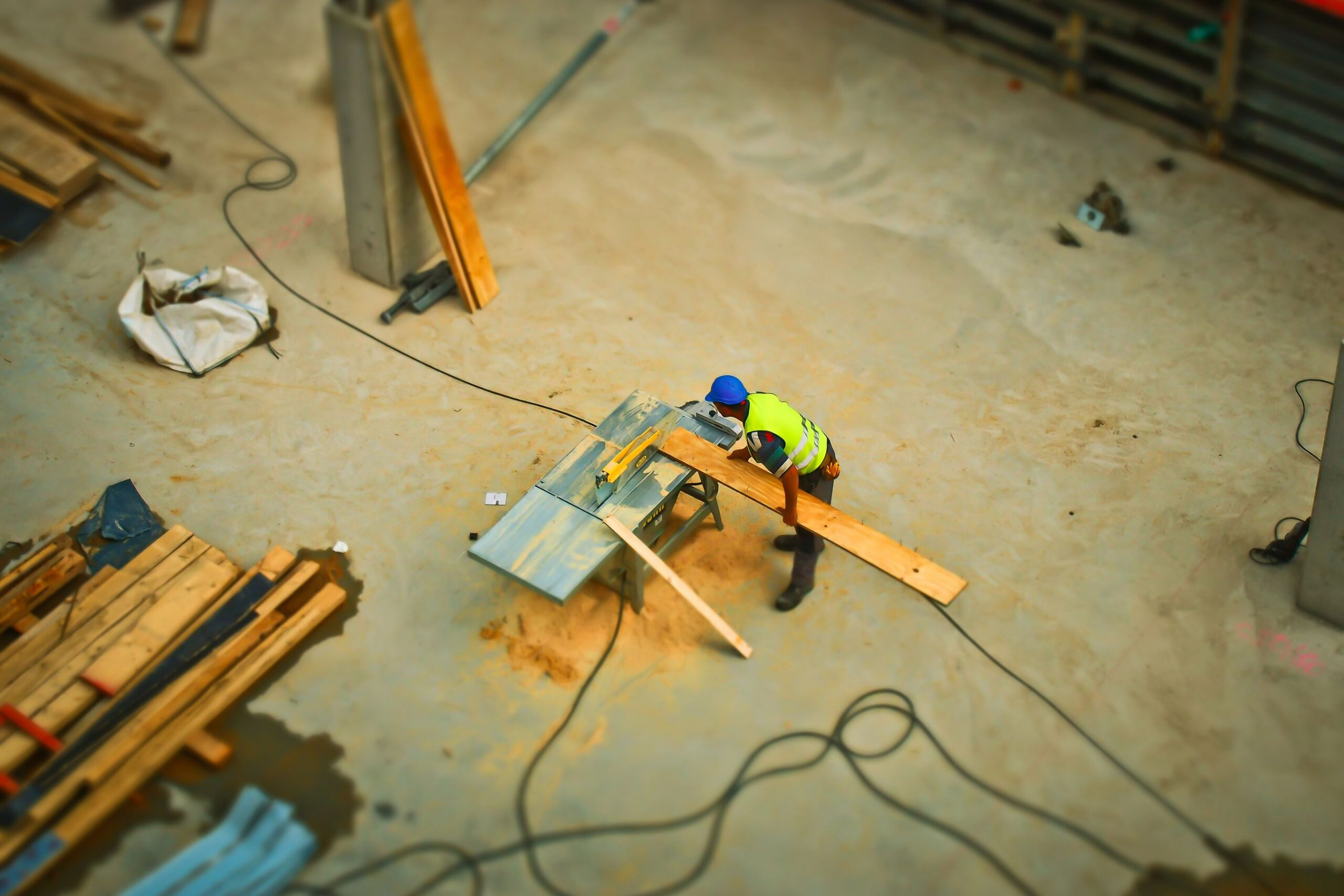 Construction worker cutting lumber with a saw on an active general contractor job site