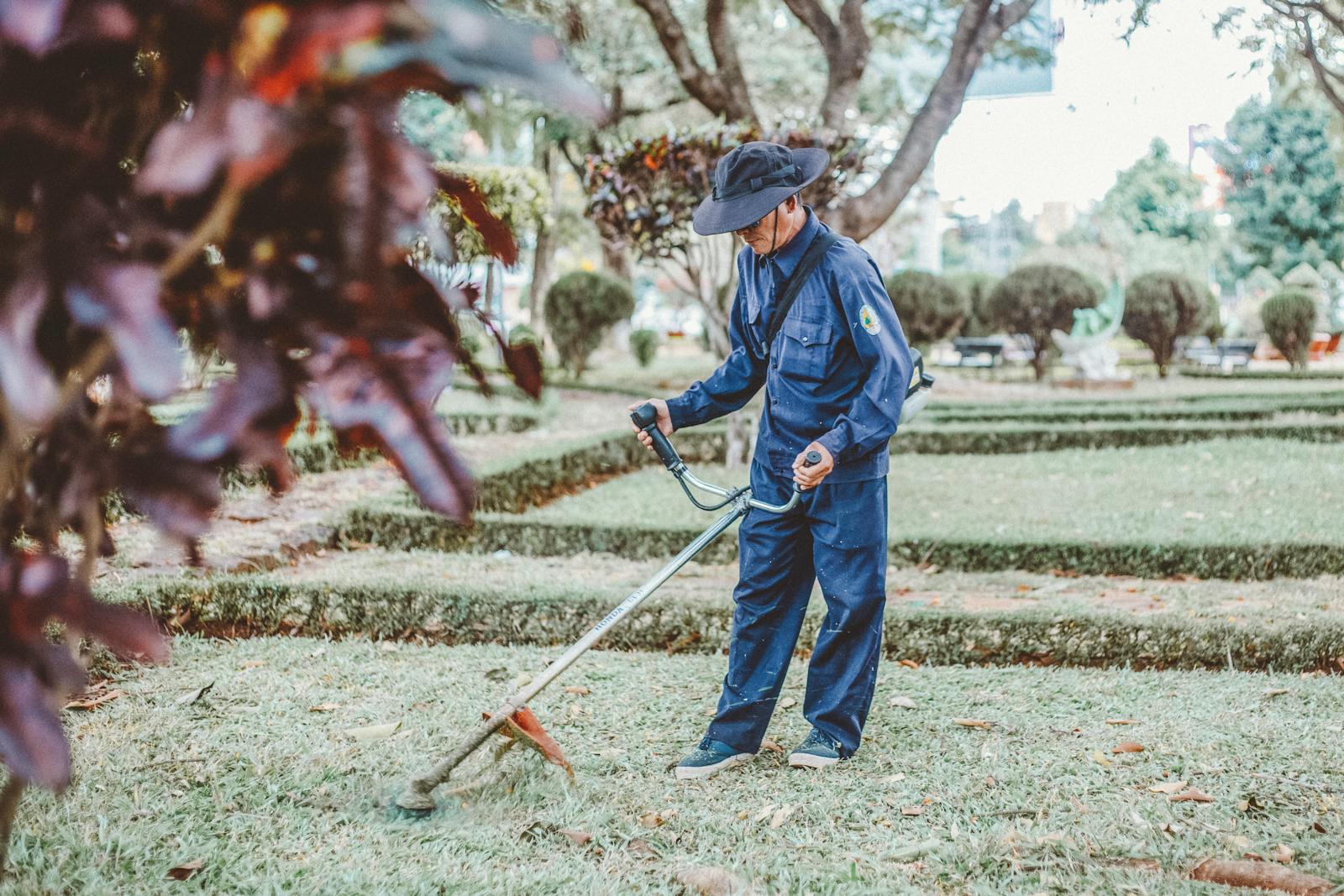 Worker using a string trimmer in a manicured park — recurring maintenance is the lifeblood of organic search demand