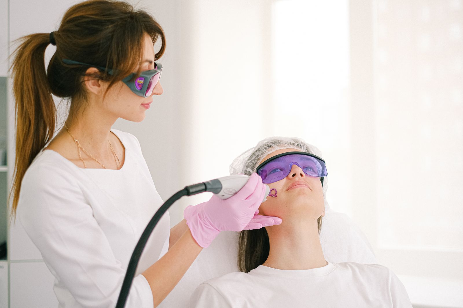 Cosmetic dermatology professional performing laser skin resurfacing treatment on a patient