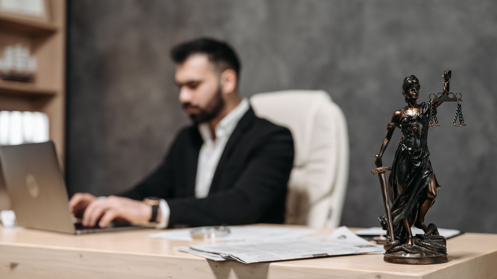 Criminal defense attorney working on a laptop with a Lady Justice statue on the desk