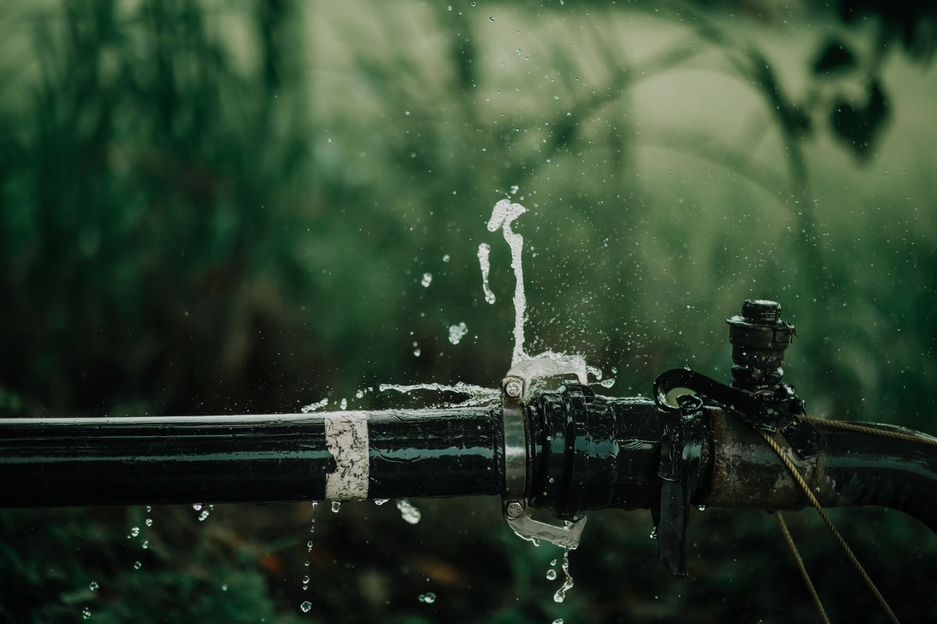 Water spraying from a leaking pipe joint outdoors
