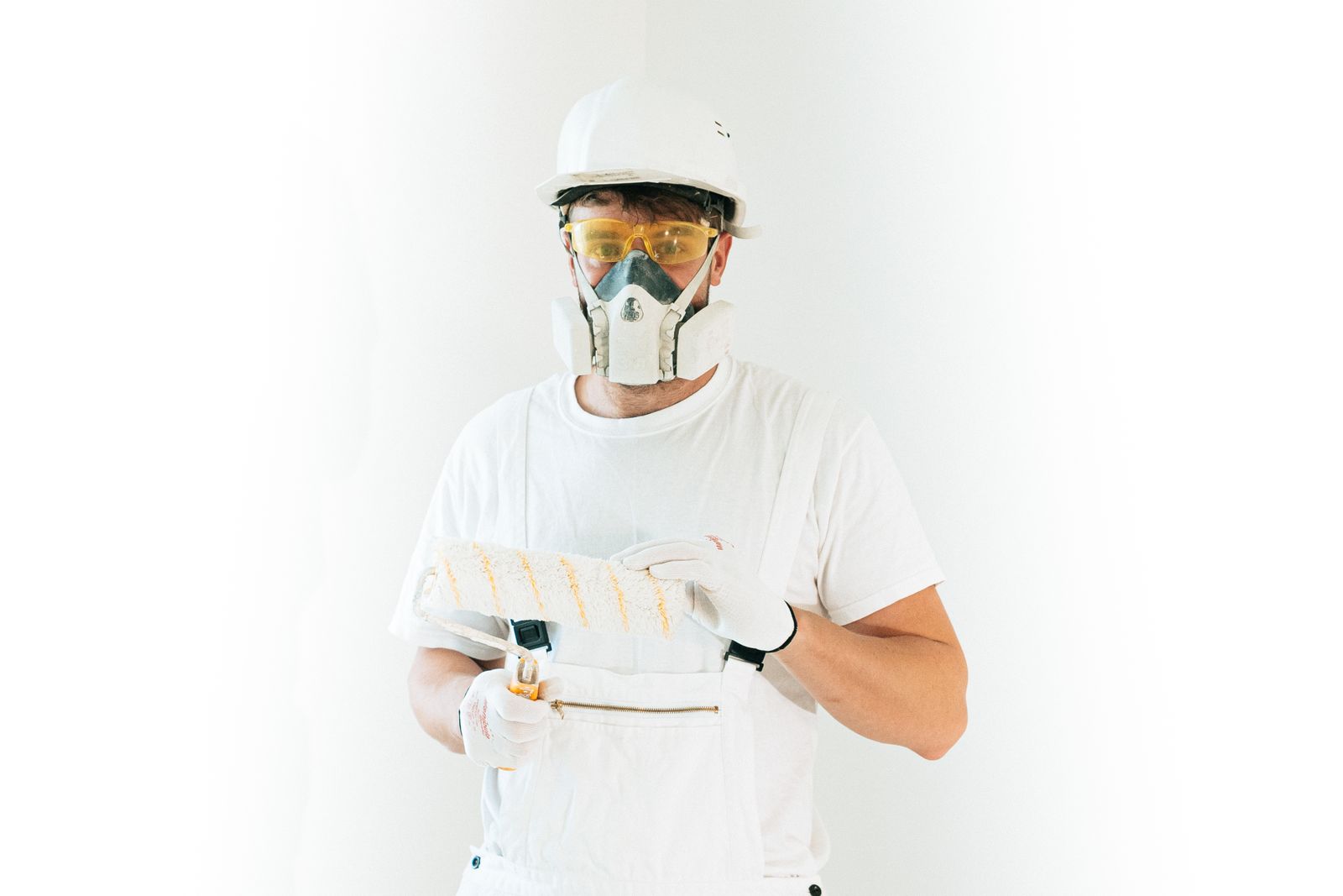 Professional house painter in protective gear holding a paint roller, ready to start a residential job