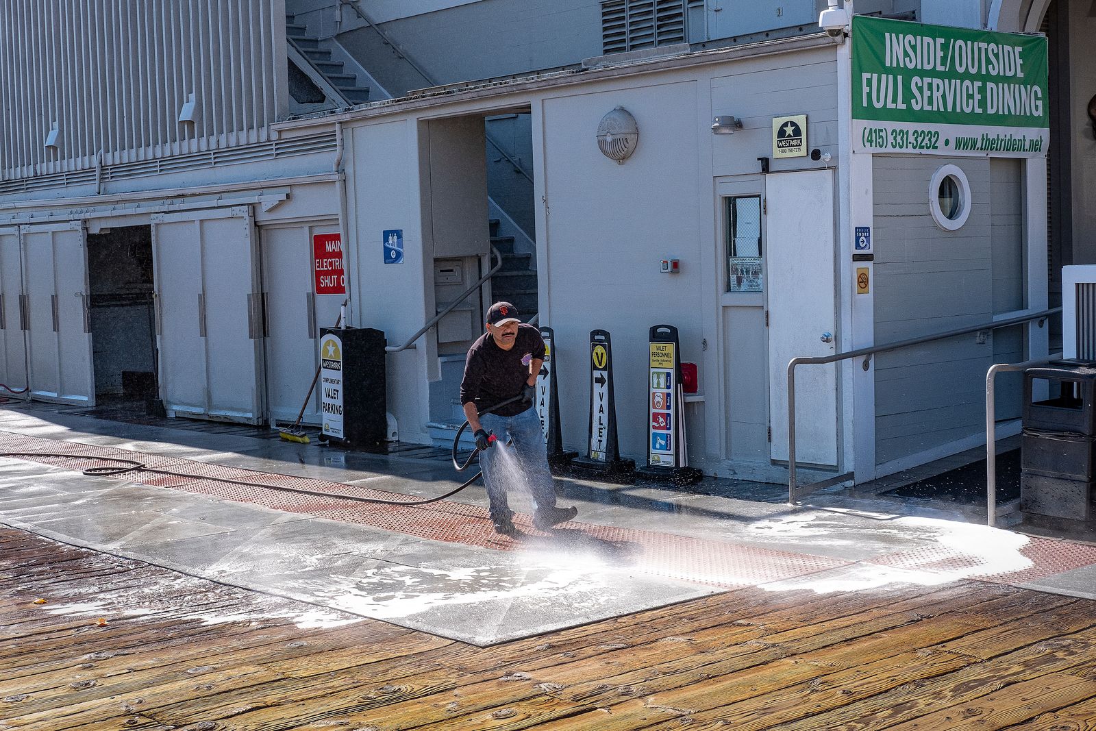 Pressure washing contractor cleaning a stained commercial sidewalk outside a restaurant