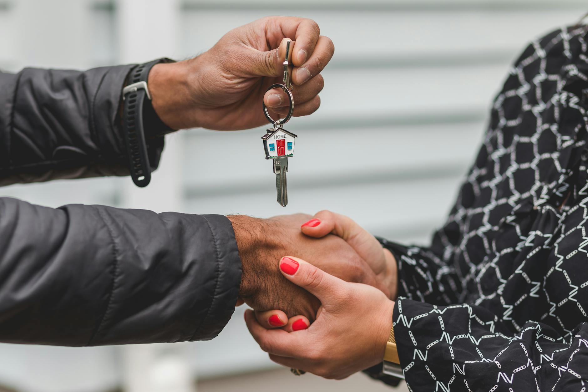 Real estate agent handing over house keys at closing with a handshake
