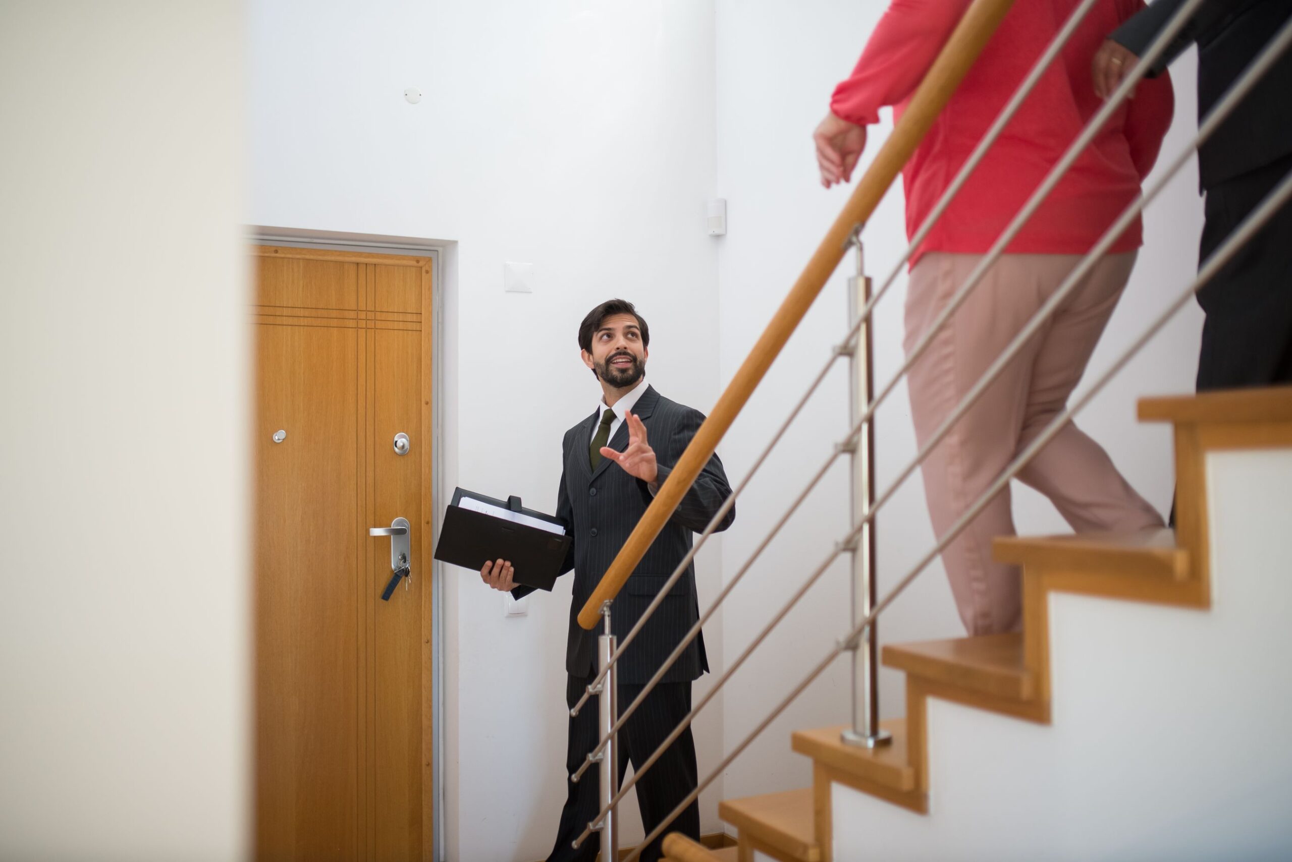 Realtor leading potential buyers on a tour up the stairs of a modern home