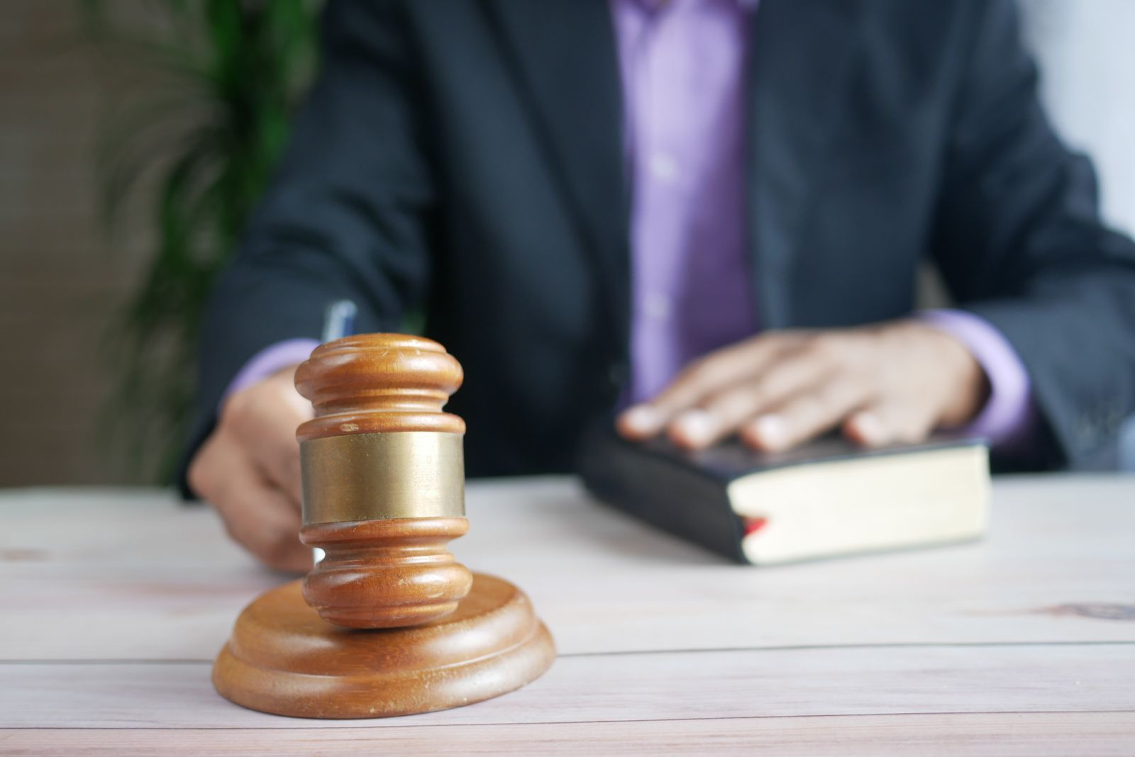 A lawyer in an office with a wooden gavel in the foreground and a law book on the desk