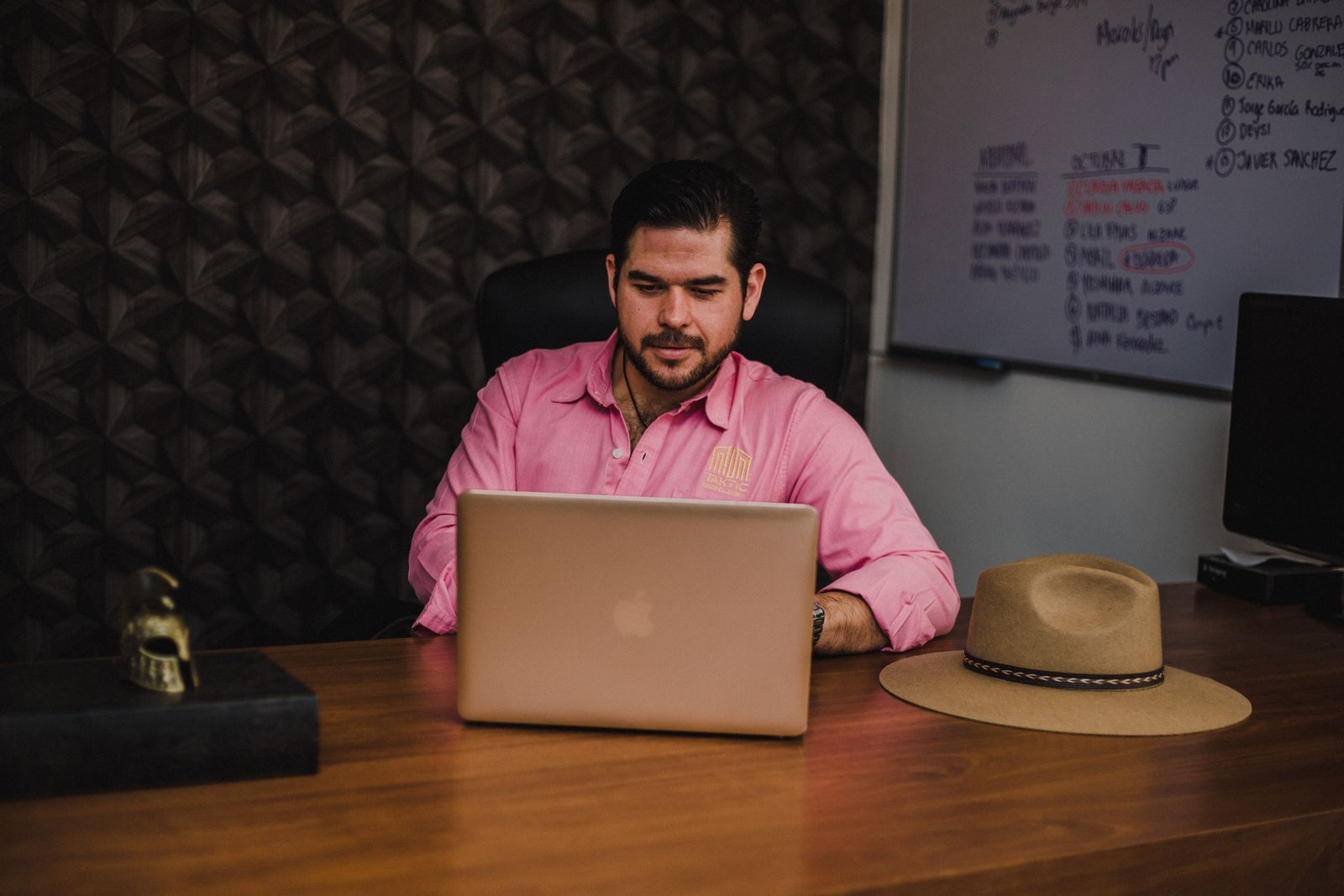 Small business owner working on a laptop at a wooden desk in his office