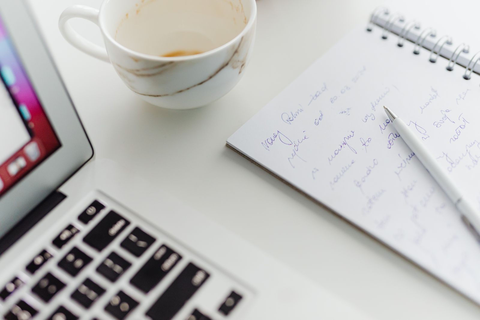 Workspace with laptop, coffee cup and handwritten notes on a notepad