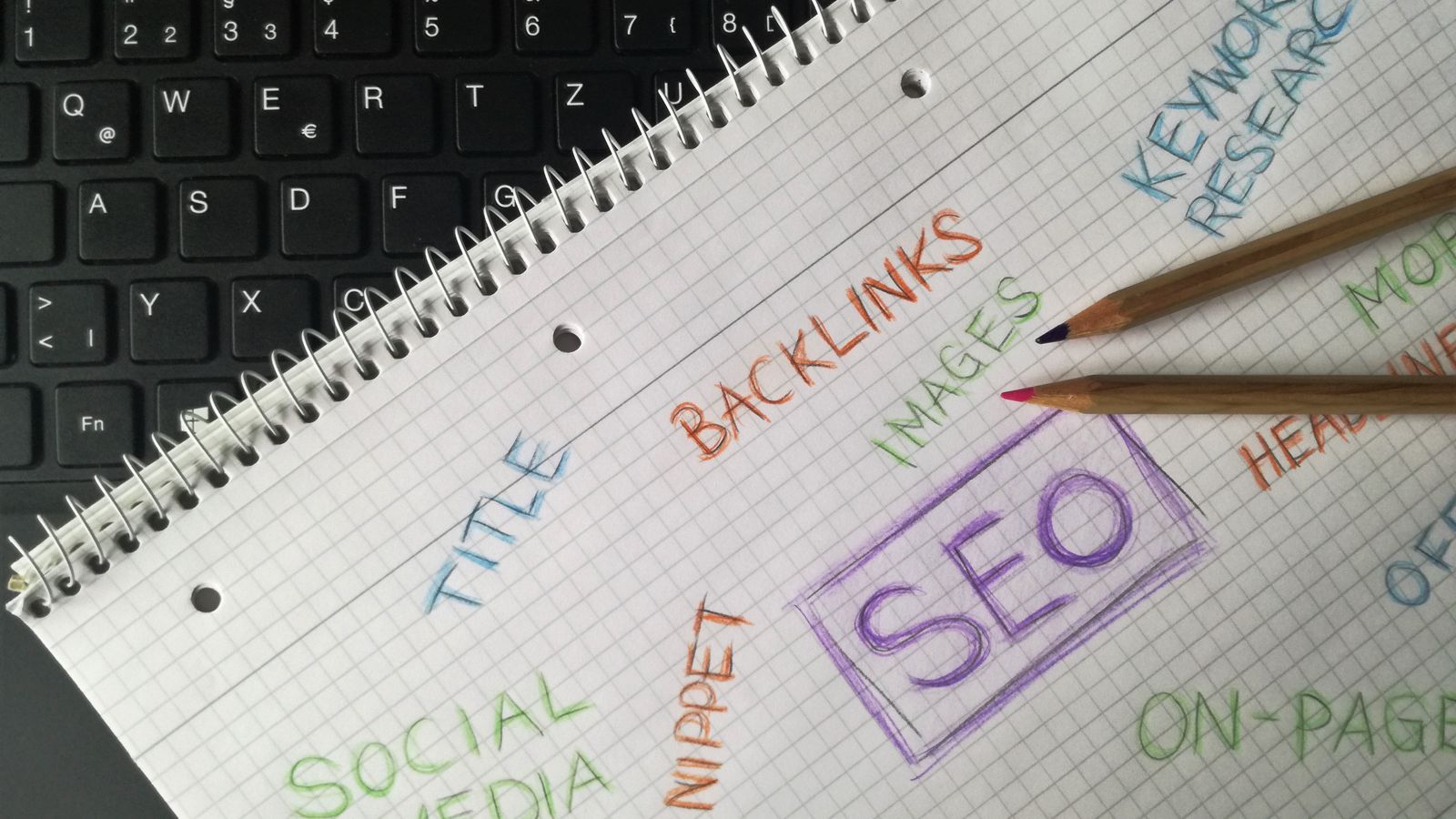 SEO keyword research notebook with handwritten terms next to laptop