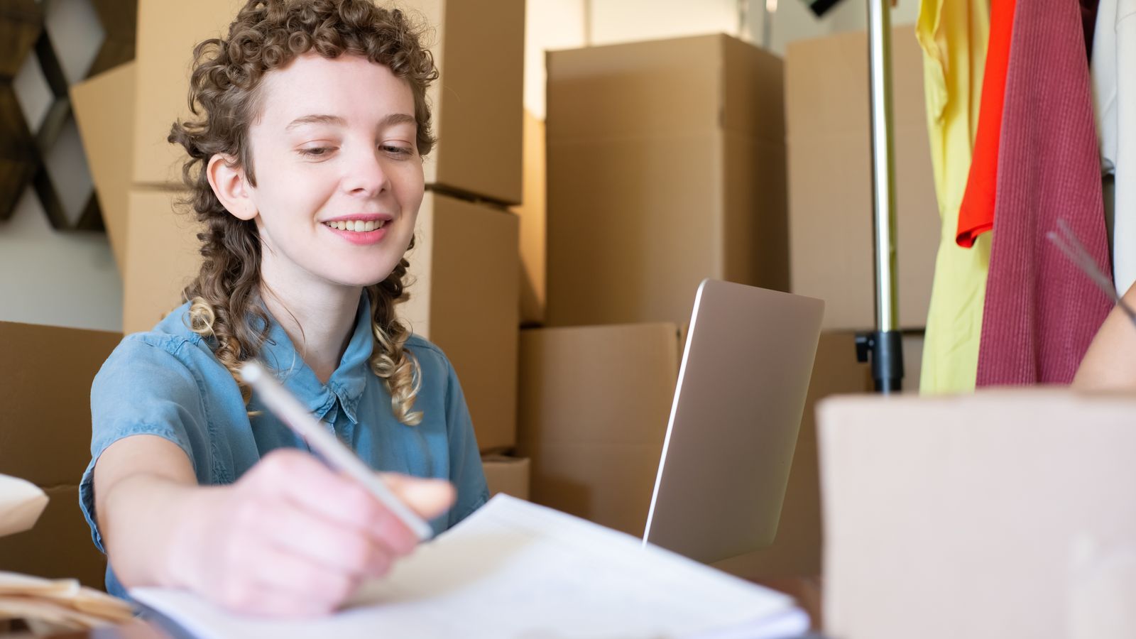 Small business owner taking notes while managing online store