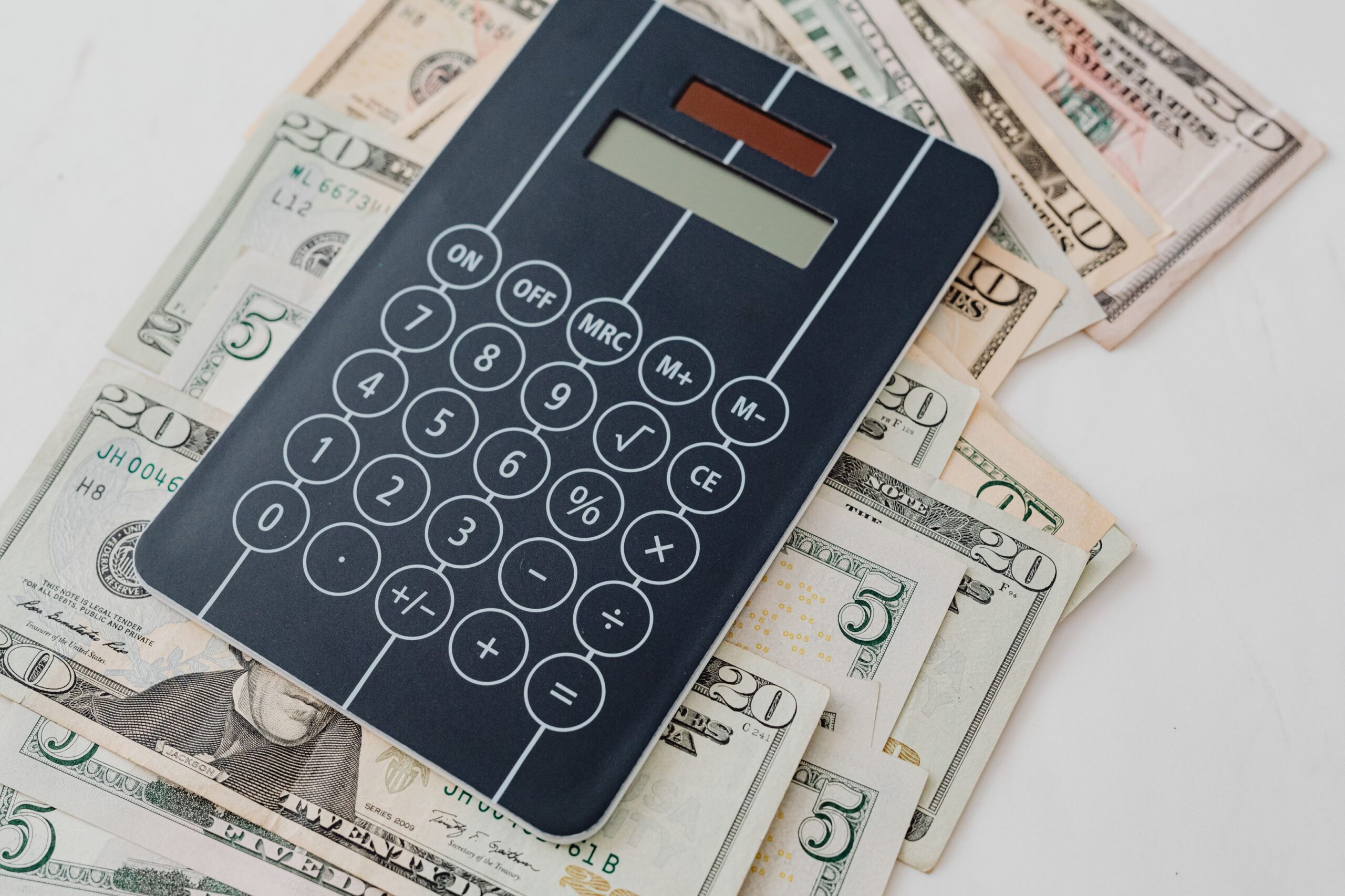 A calculator resting on a spread of U.S. dollar bills, representing the cost of SEO for a small business