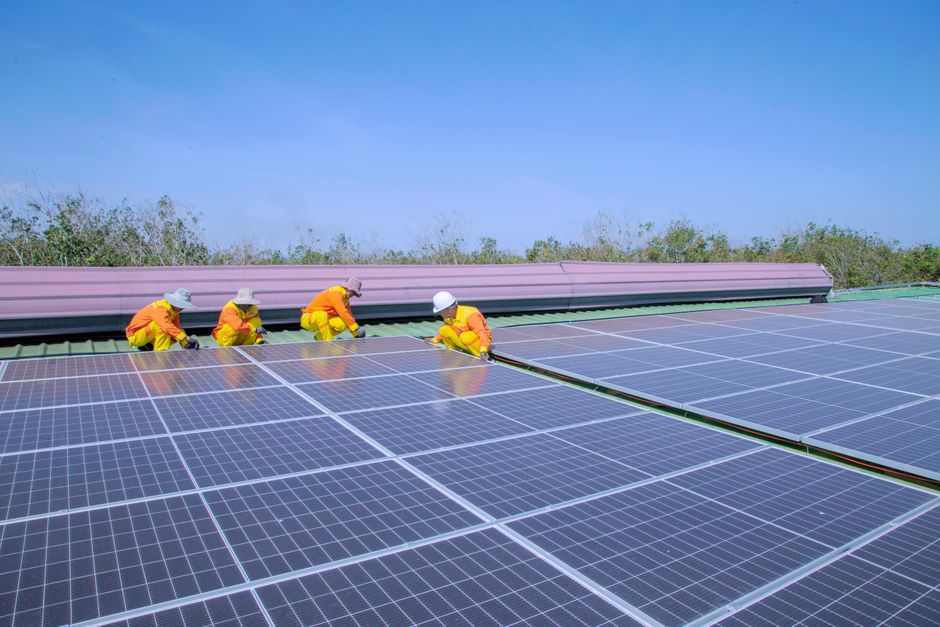 Solar installation team mounting panels on a residential metal roof on a sunny day