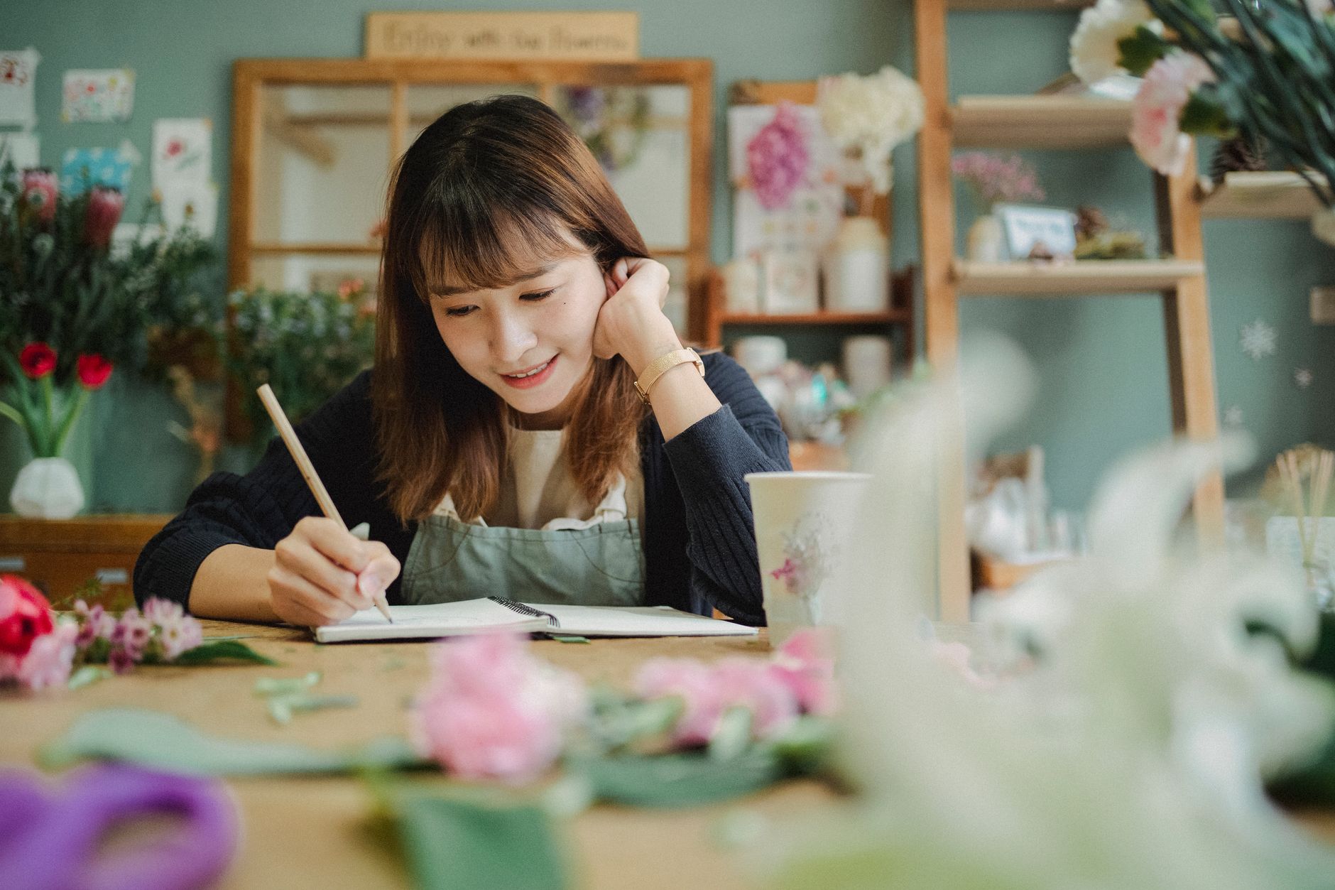 Small business owner planning content strategy and writing notes in her shop