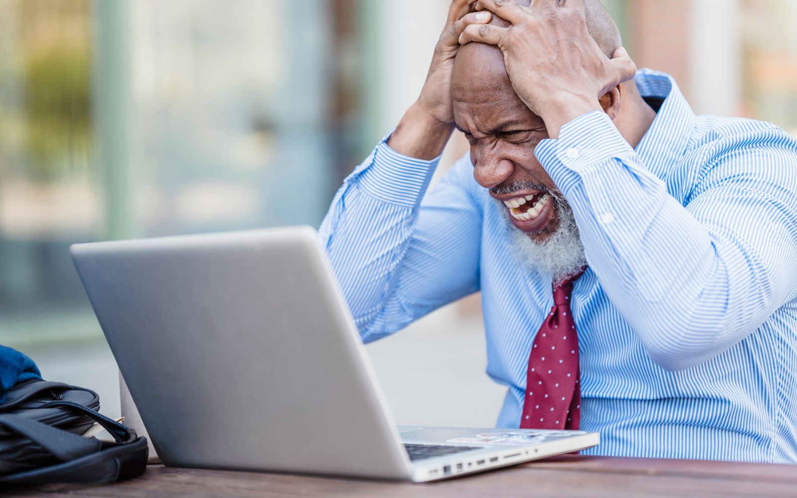 Stressed business owner with hands on head looking at laptop — the frustration that drives service pros to abandon lead-credit platforms