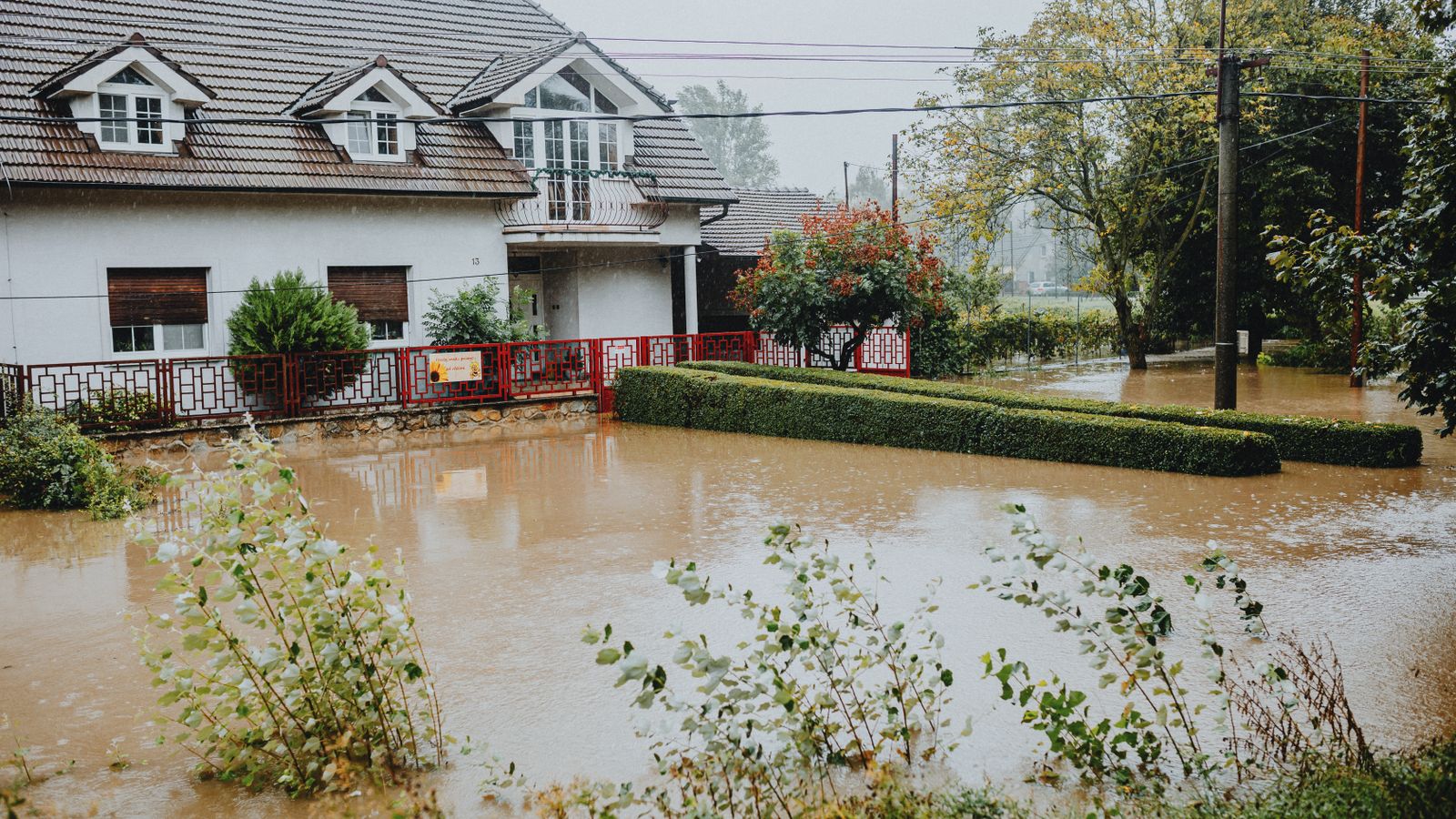 Suburban home surrounded by floodwaters after heavy rainfall, typical scenario for a water damage restoration call