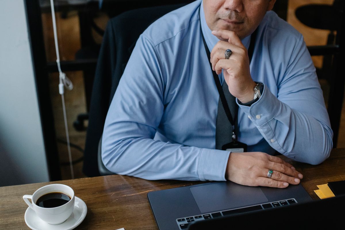 Business professional reviewing SEO keyword notes at desk with laptop and coffee