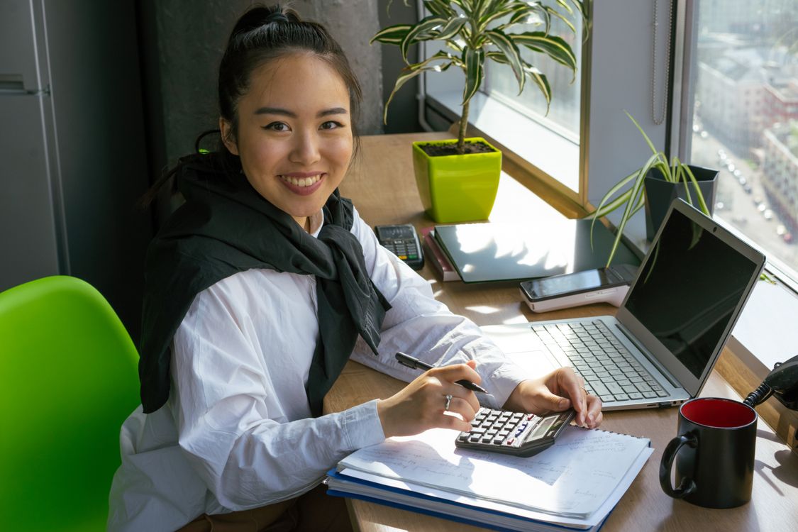 Accountant smiling at desk with calculator and financial reports