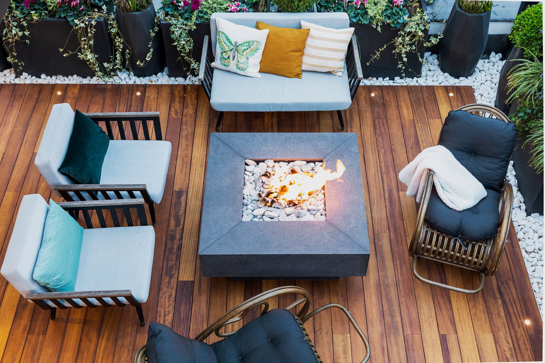 Overhead view of a wood deck styled with a fire pit and cushioned outdoor seating