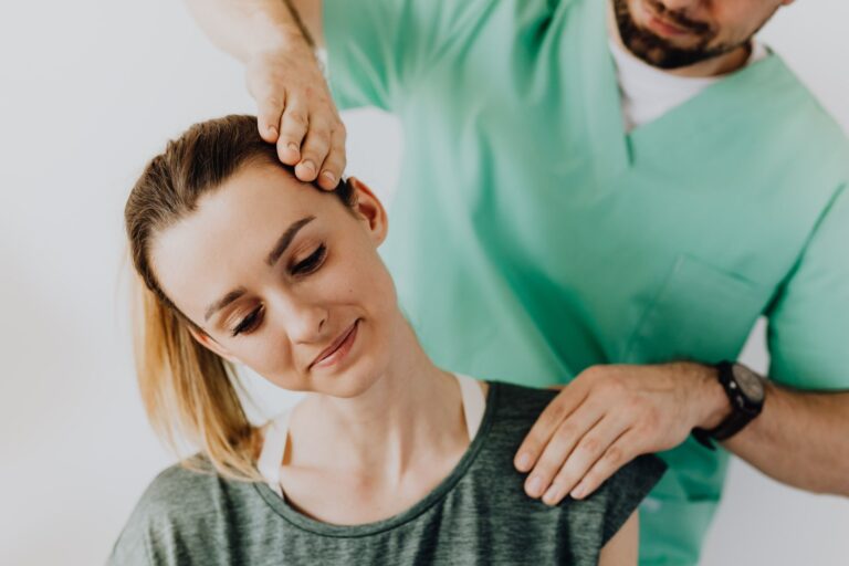 Chiropractor in scrubs performing a gentle neck adjustment on a patient in a clinic